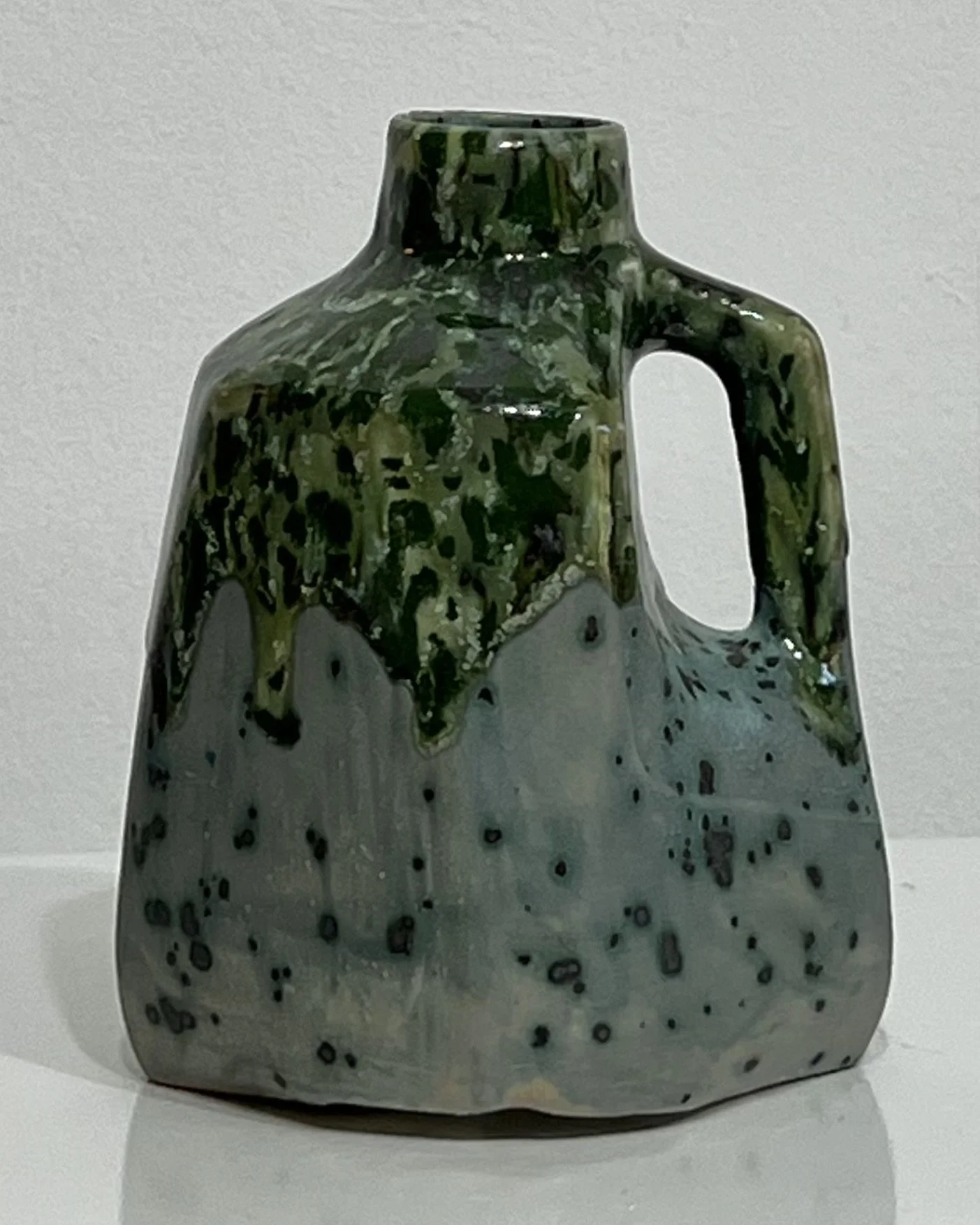 Front view of porcelain milk jug 26.122 with green and speckled Moonscape glaze