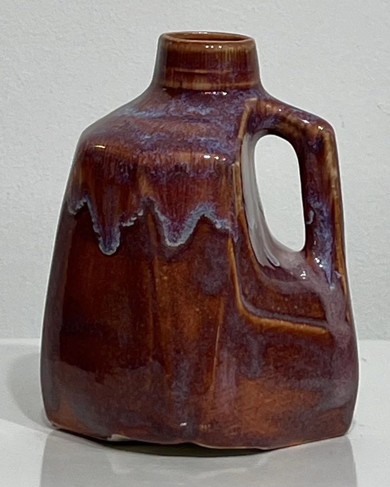 Front view of burgundy porcelain milk jug with soft lavender-cream glaze patterns