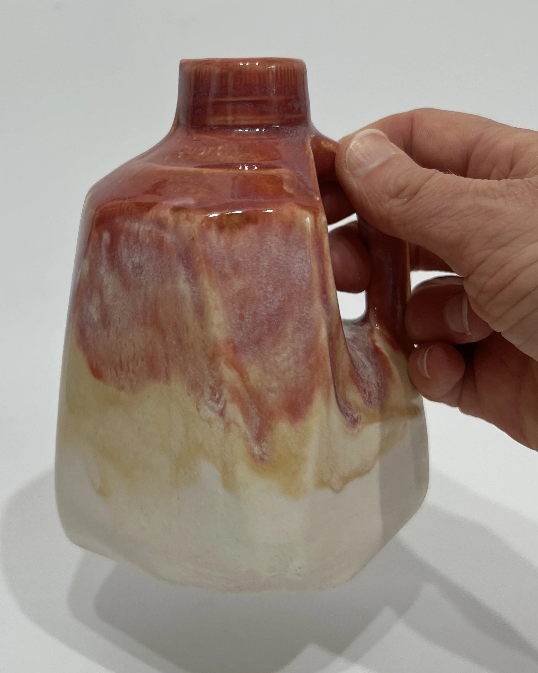 Small handmade porcelain milk jug held in a hand to demonstrate its size