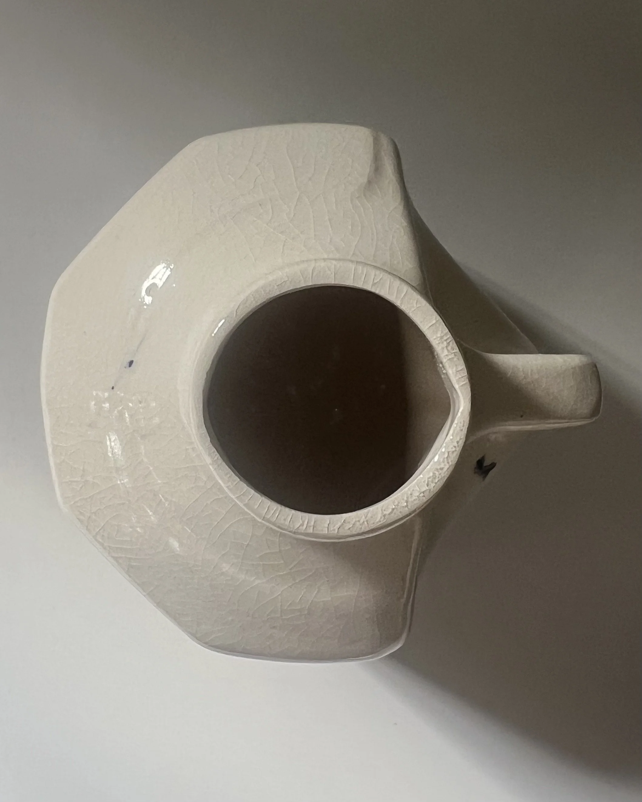 Top view of the opening of a handbuilt porcelain milk jug with glossy glazed interior.