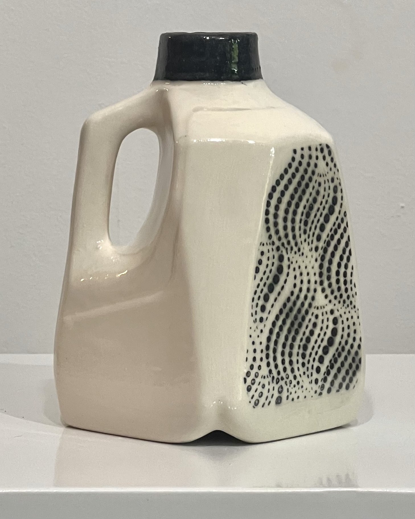 Rear view of handmade ceramic milk jug vase with cream glaze and dark blue neck.