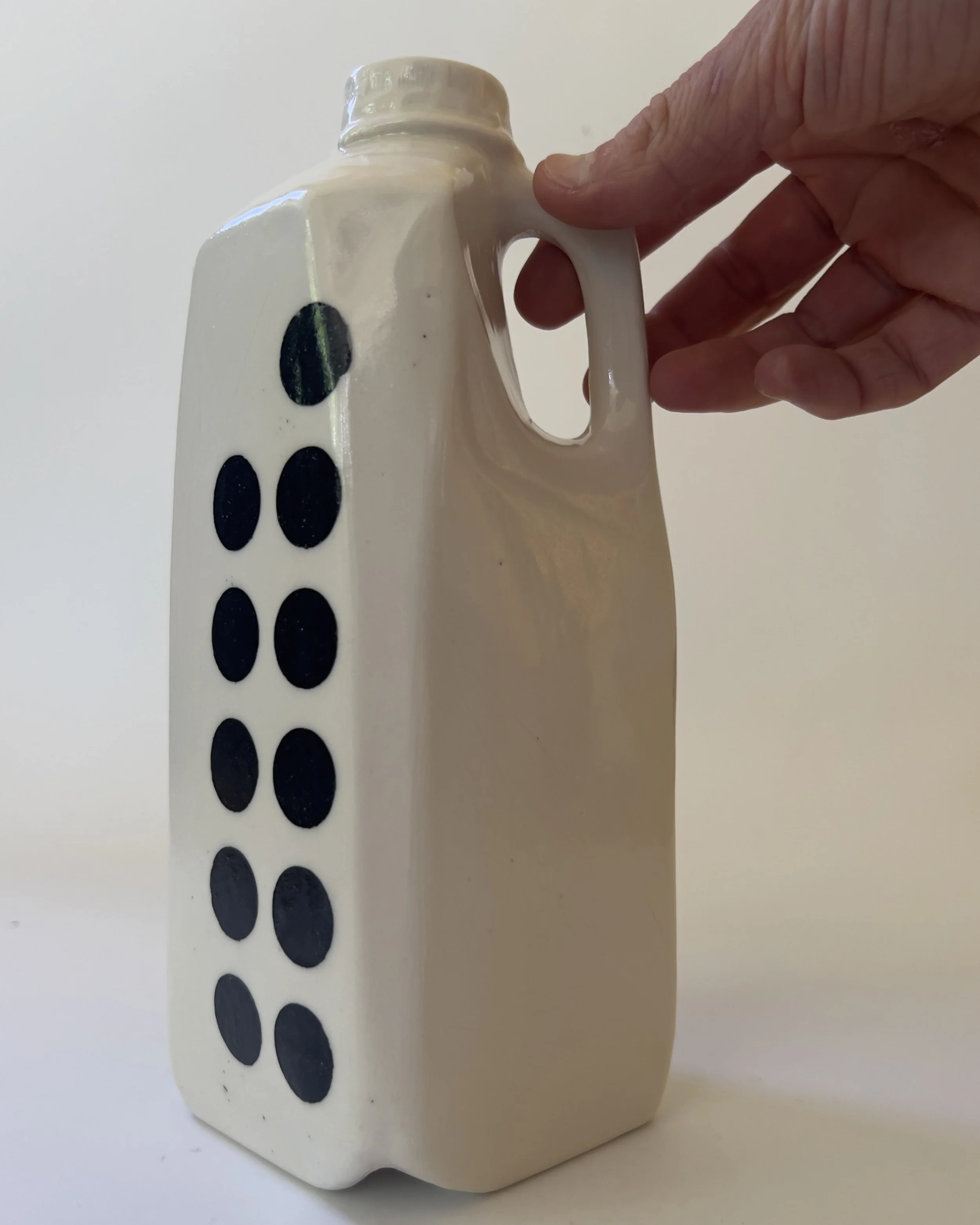 Hand holding handmade ceramic tall jug vase for scale reference