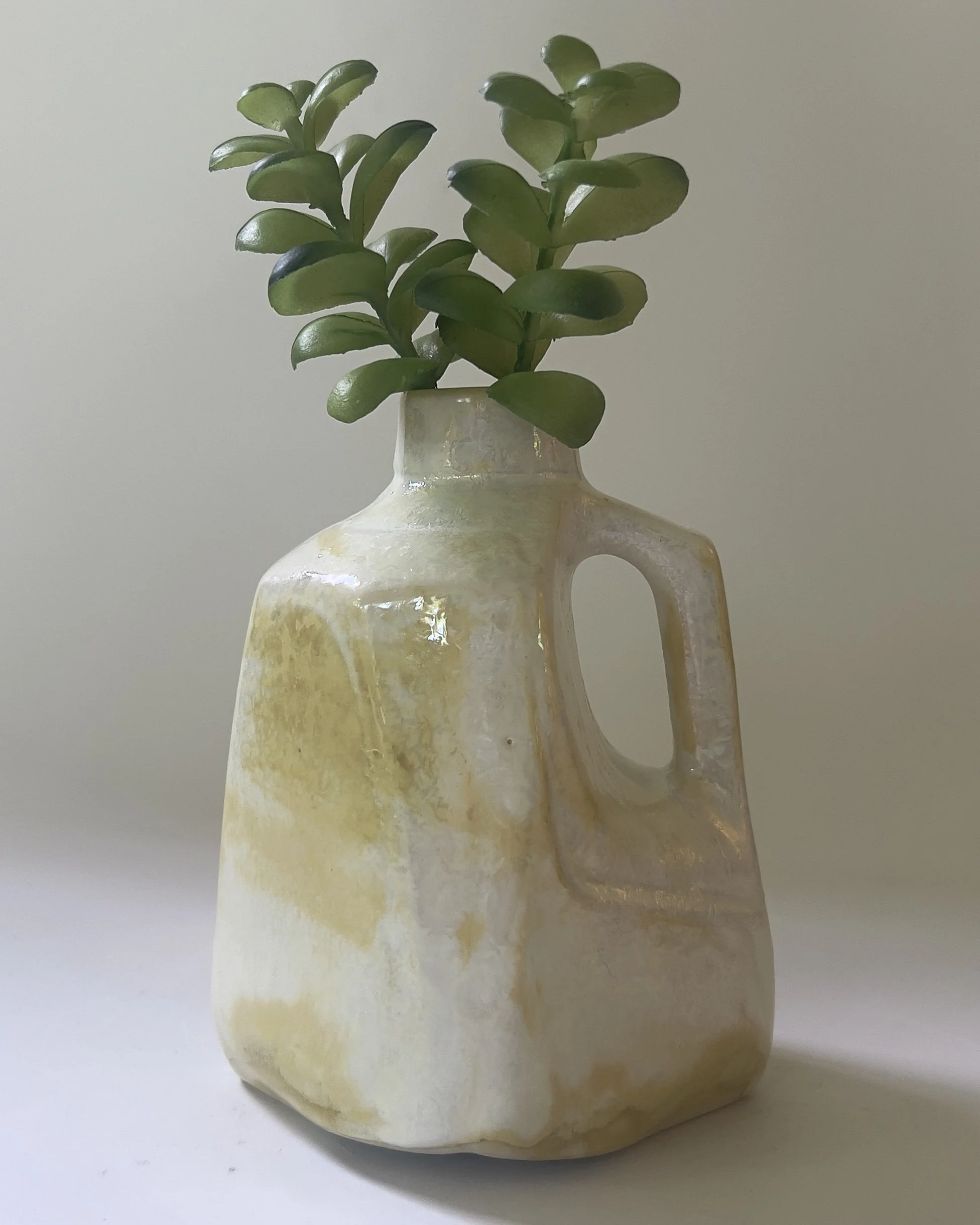 Back view of contemporary ceramic vessel with creamy pearl glaze and faceted form