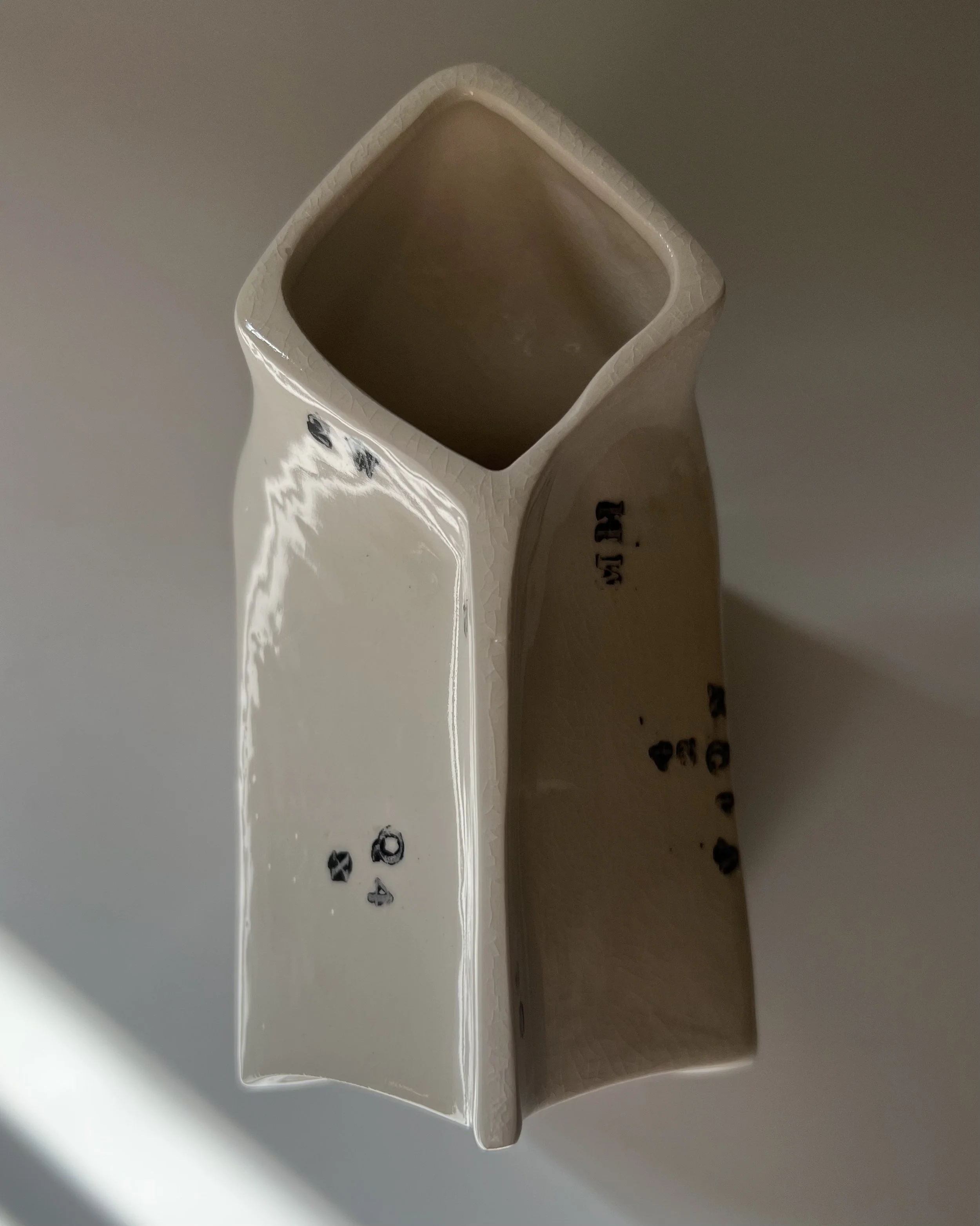 Top view of the folded opening of a handbuilt porcelain milk carton with glossy glazed interior.