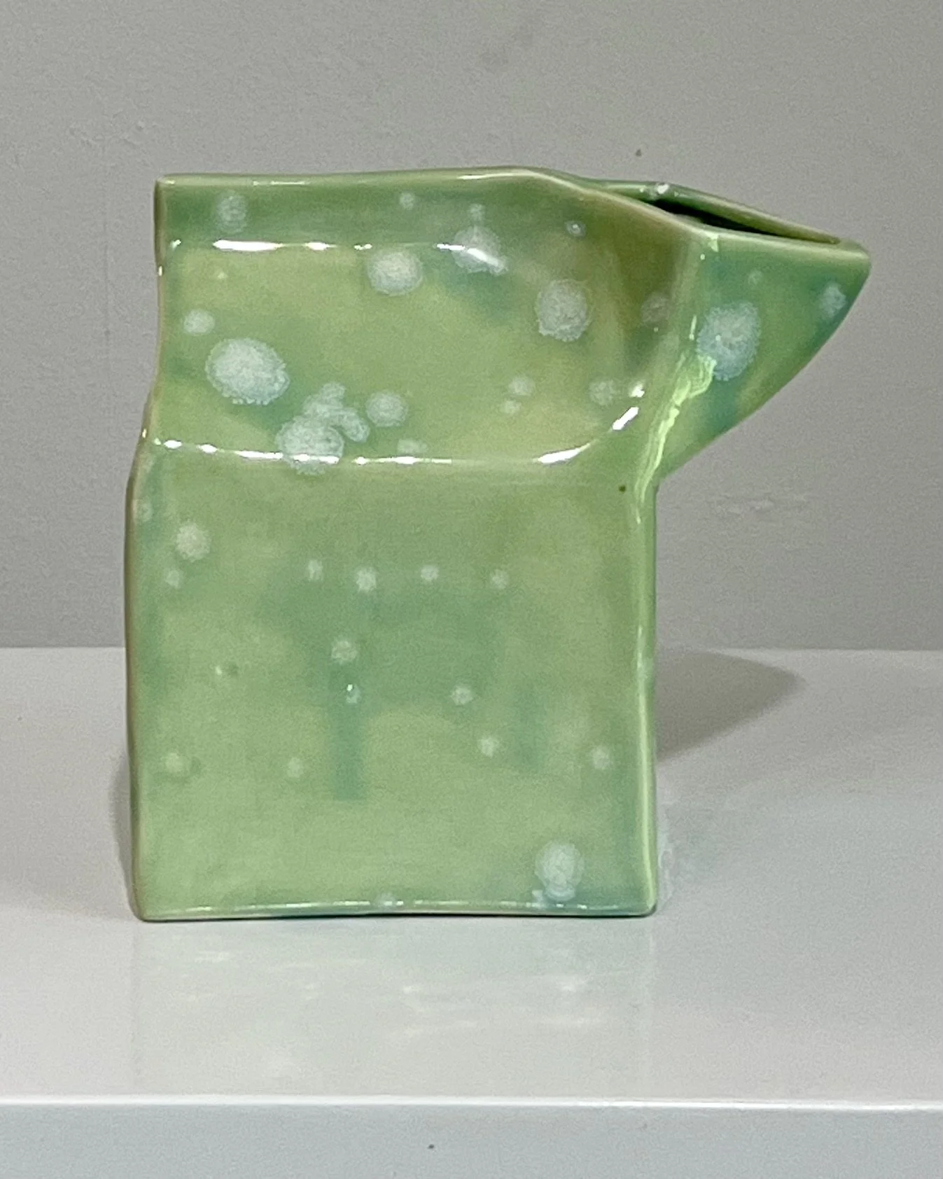 Back view showing soft celadon glaze variations over the sculptural vessel.