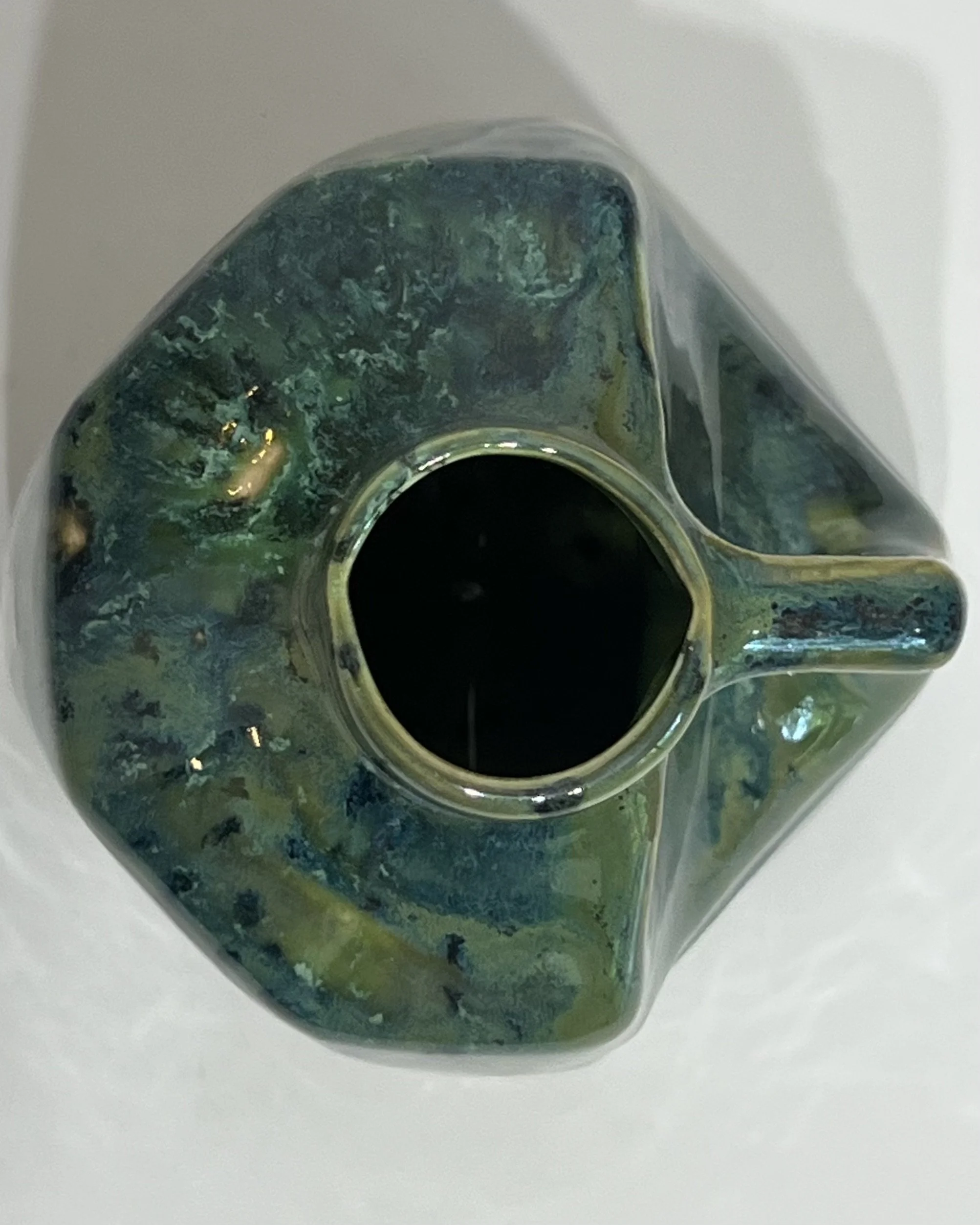 Top view of handmade porcelain milk jug showing its opening and surrounding green ceramic glaze.