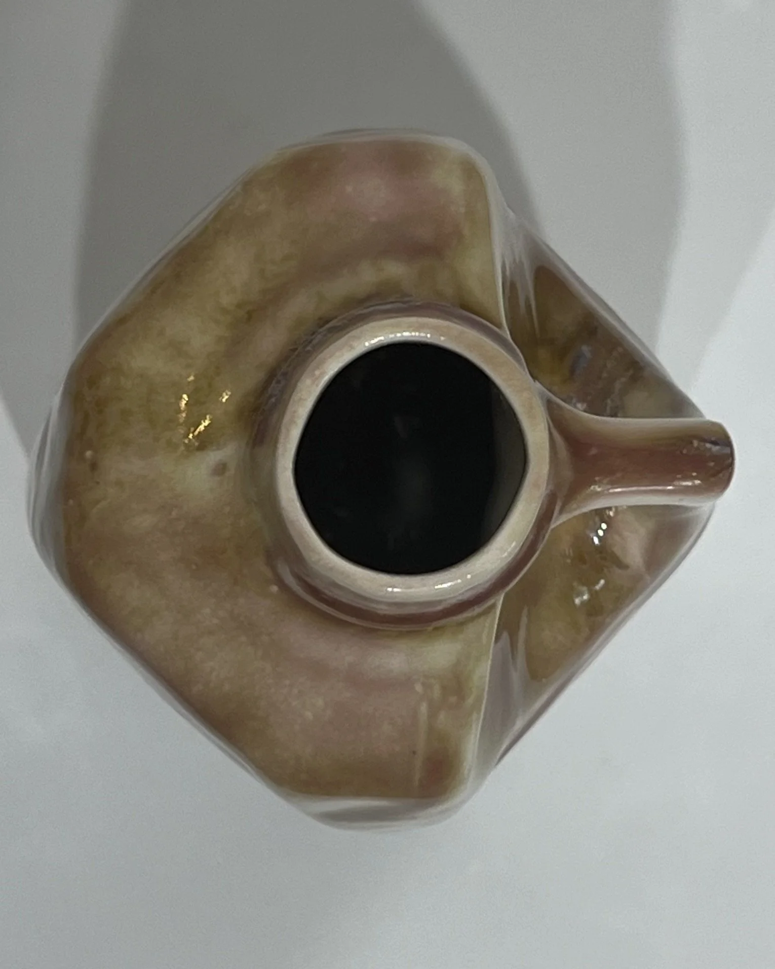 Top view of handmade ceramic milk jug showing the vessel opening and softly variegated pink, olive, and cream glaze.