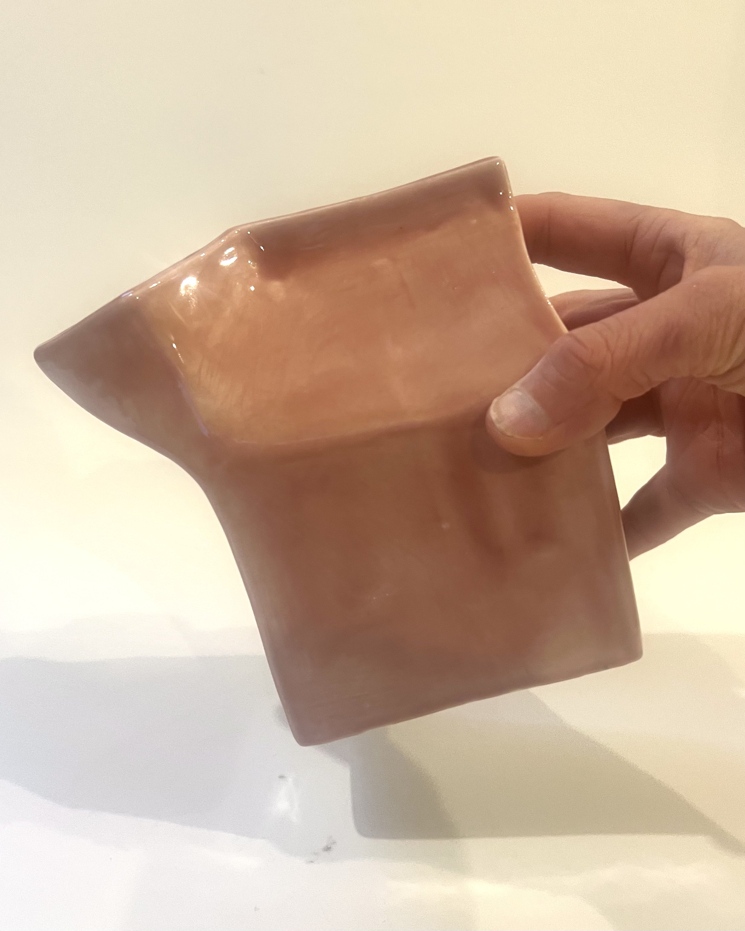 Blush porcelain milk carton sculpture held in hand for scale, handmade contemporary ceramic vessel approximately 6 inches tall.