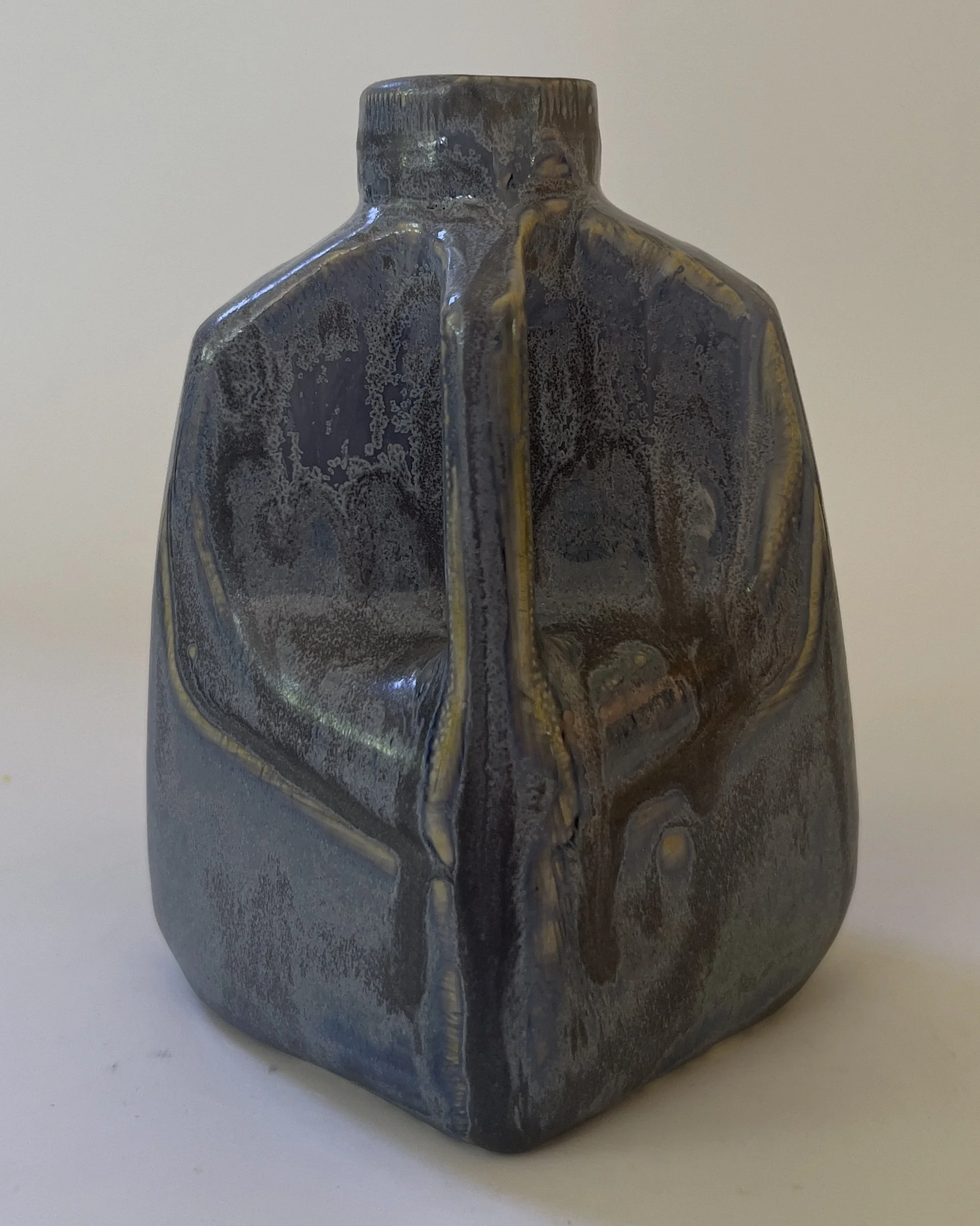 Rear view of handmade ceramic jug vase showing faceted sculptural form and flowing glaze