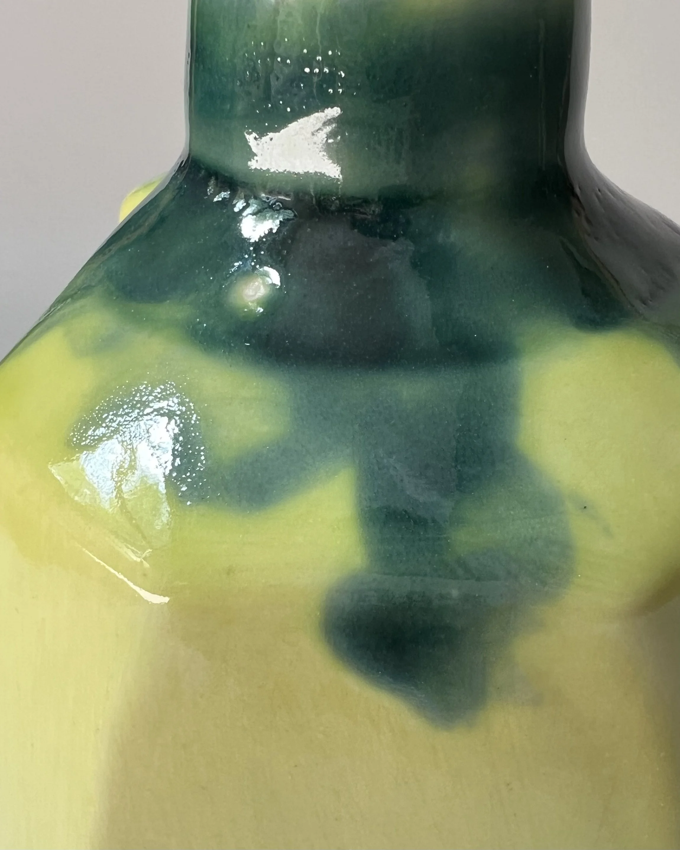 Close-up of the flowing lime green and dark green glaze detail on a porcelain milk jug.