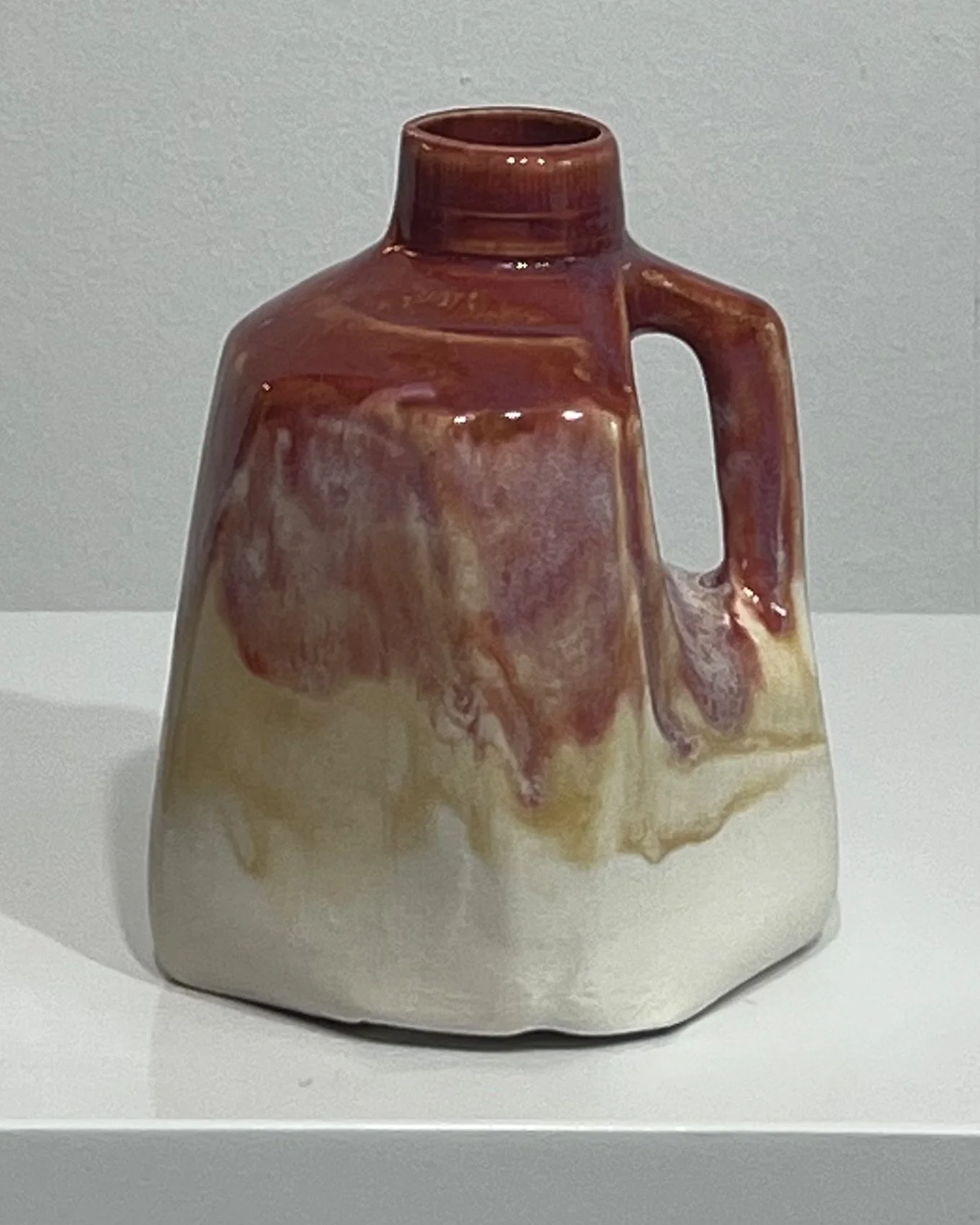Handmade porcelain milk jug with deep plum-red glaze transitioning into honey gold and creamy ivory