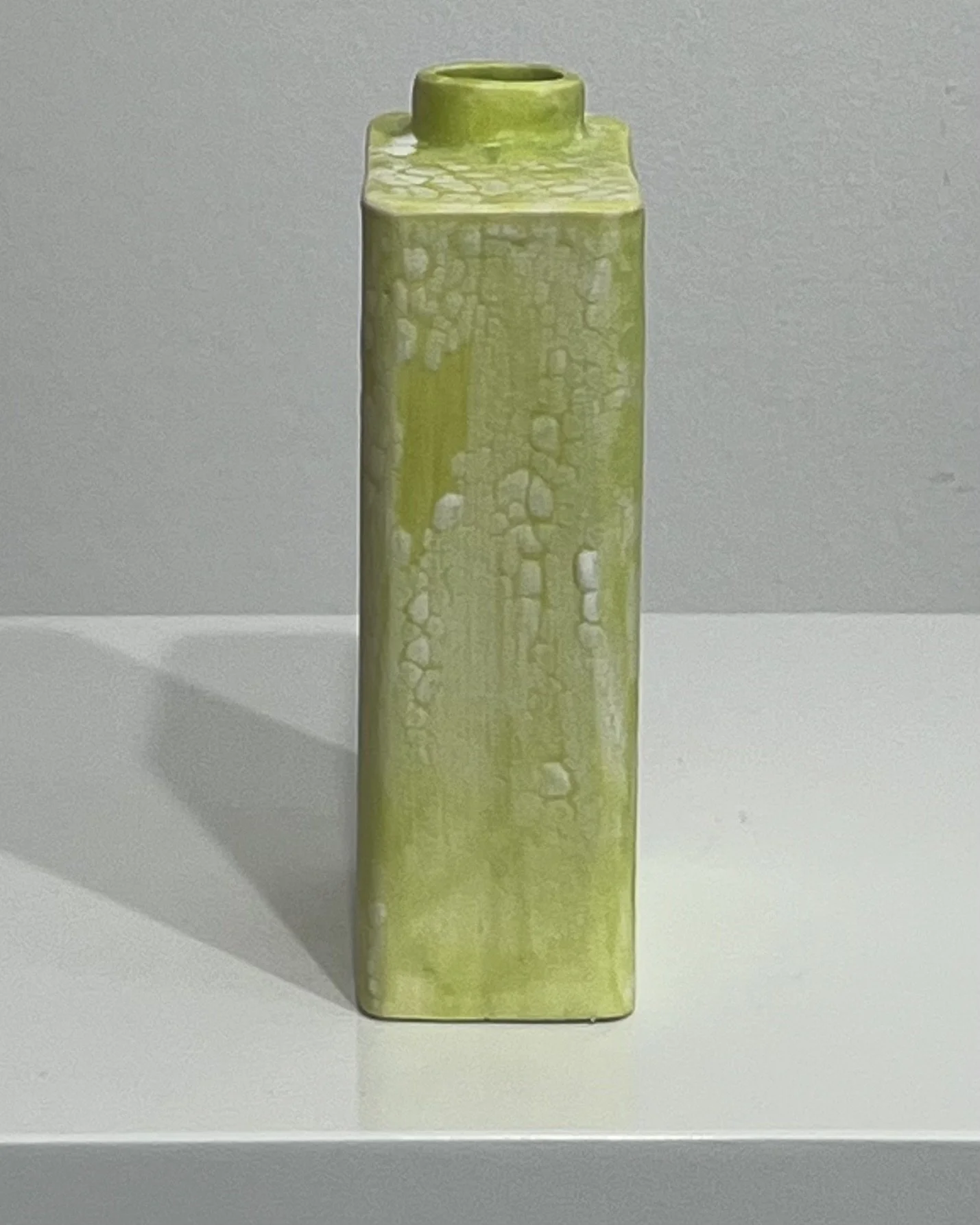 Right-side view of sculptural porcelain Carton vessel with bright yellow-green and pale textured-looking glaze.