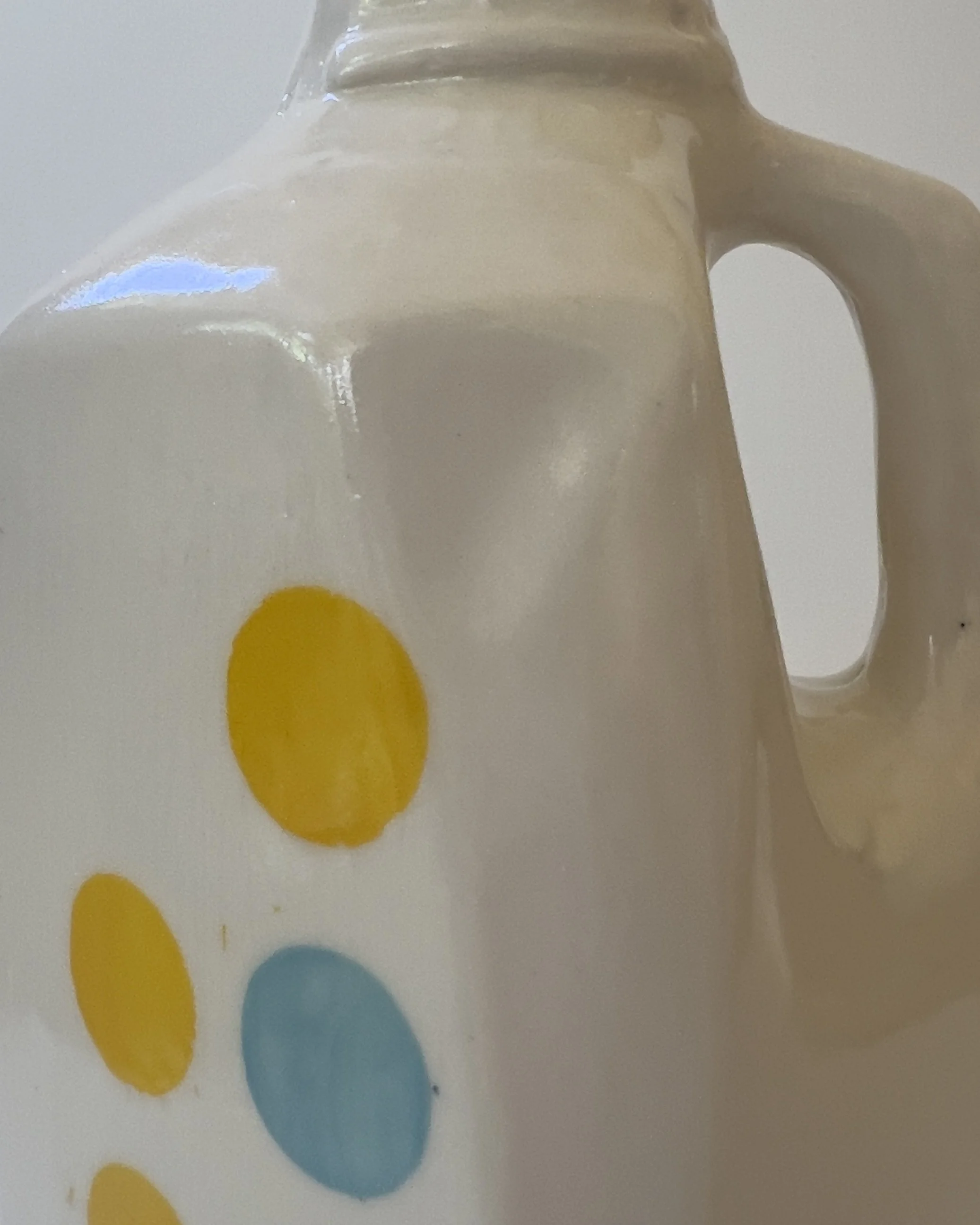 Close-up detail of glossy pearlescent glaze and yellow dot pattern