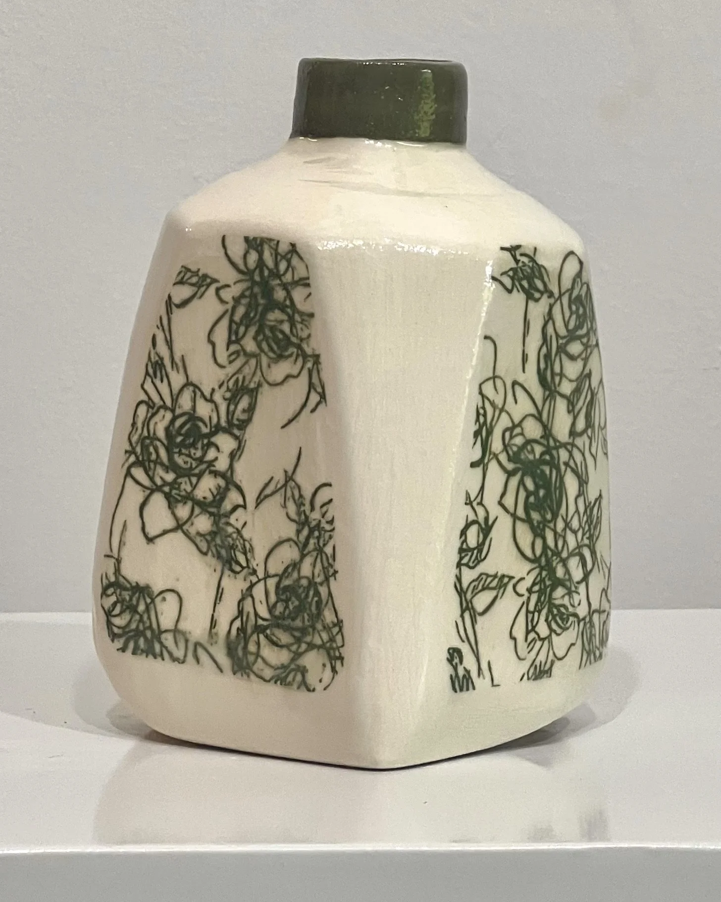 Three-quarter view of Verdant Sketch handmade porcelain milk jug vase with green botanical transfer wrapping around the form.
