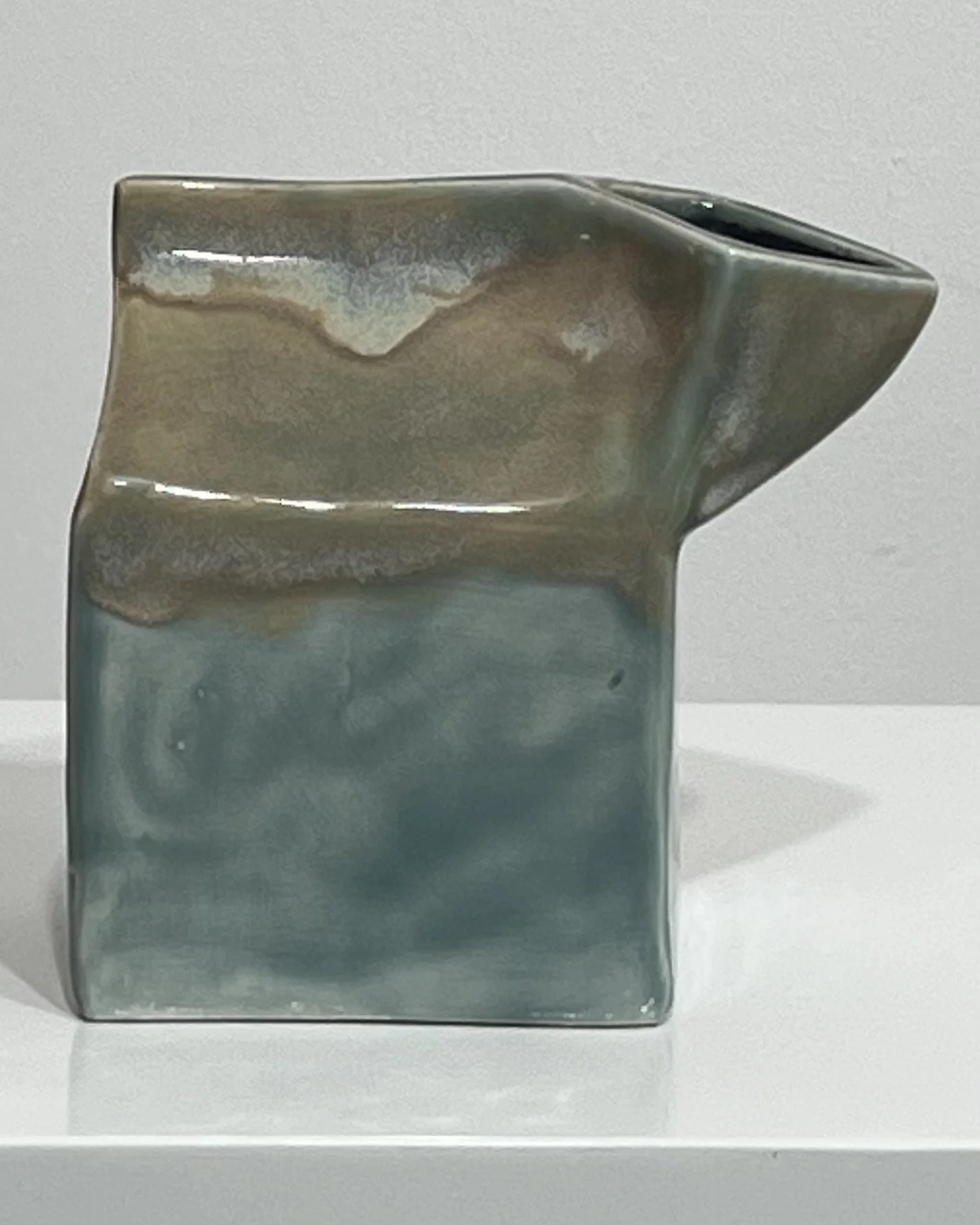 Side view of ceramic milk carton with soft blue-green glaze and warm neutral glaze along the top.