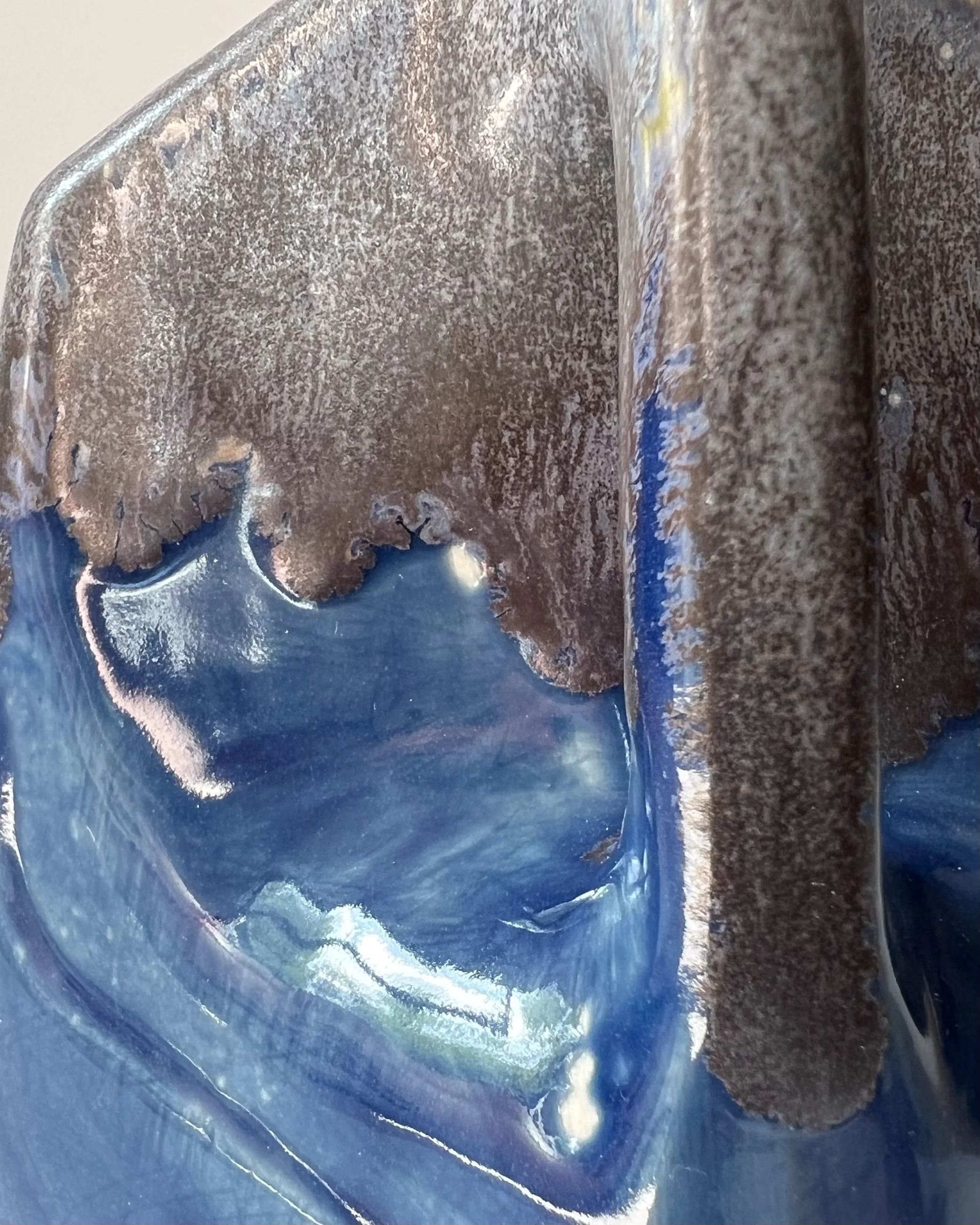 Close-up of the layered cobalt blue and smoky gray glaze flowing across the porcelain surface.
