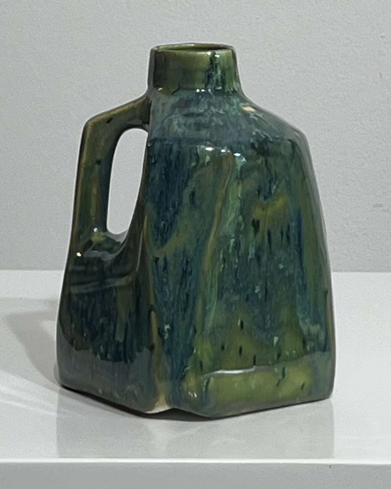 Back view of handmade ceramic milk jug featuring deep green and turquoise glaze movement.