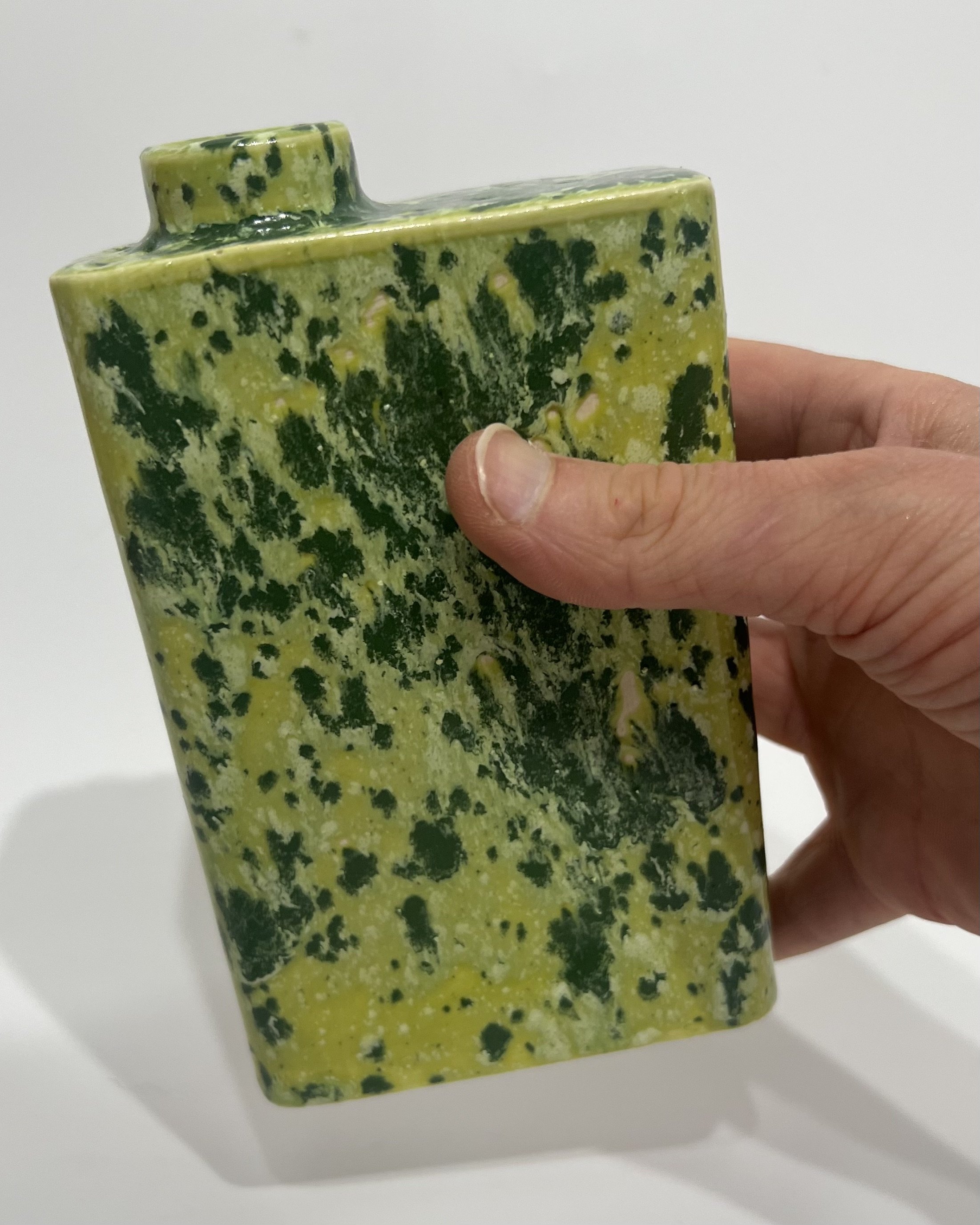 Handmade green porcelain carton held in hand to demonstrate its compact size