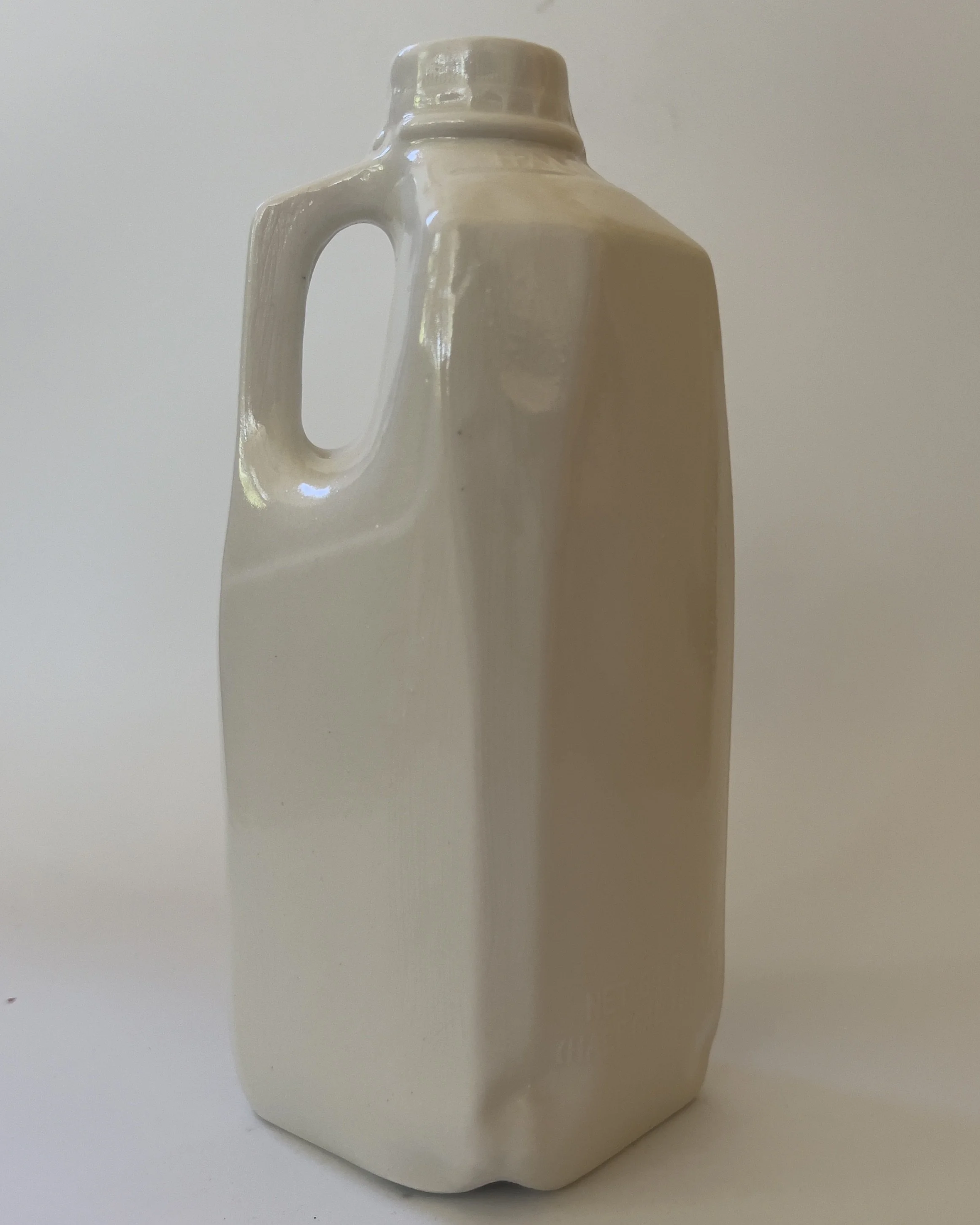 Side view of sculptural ceramic jug vase with integrated handle and glossy white glaze