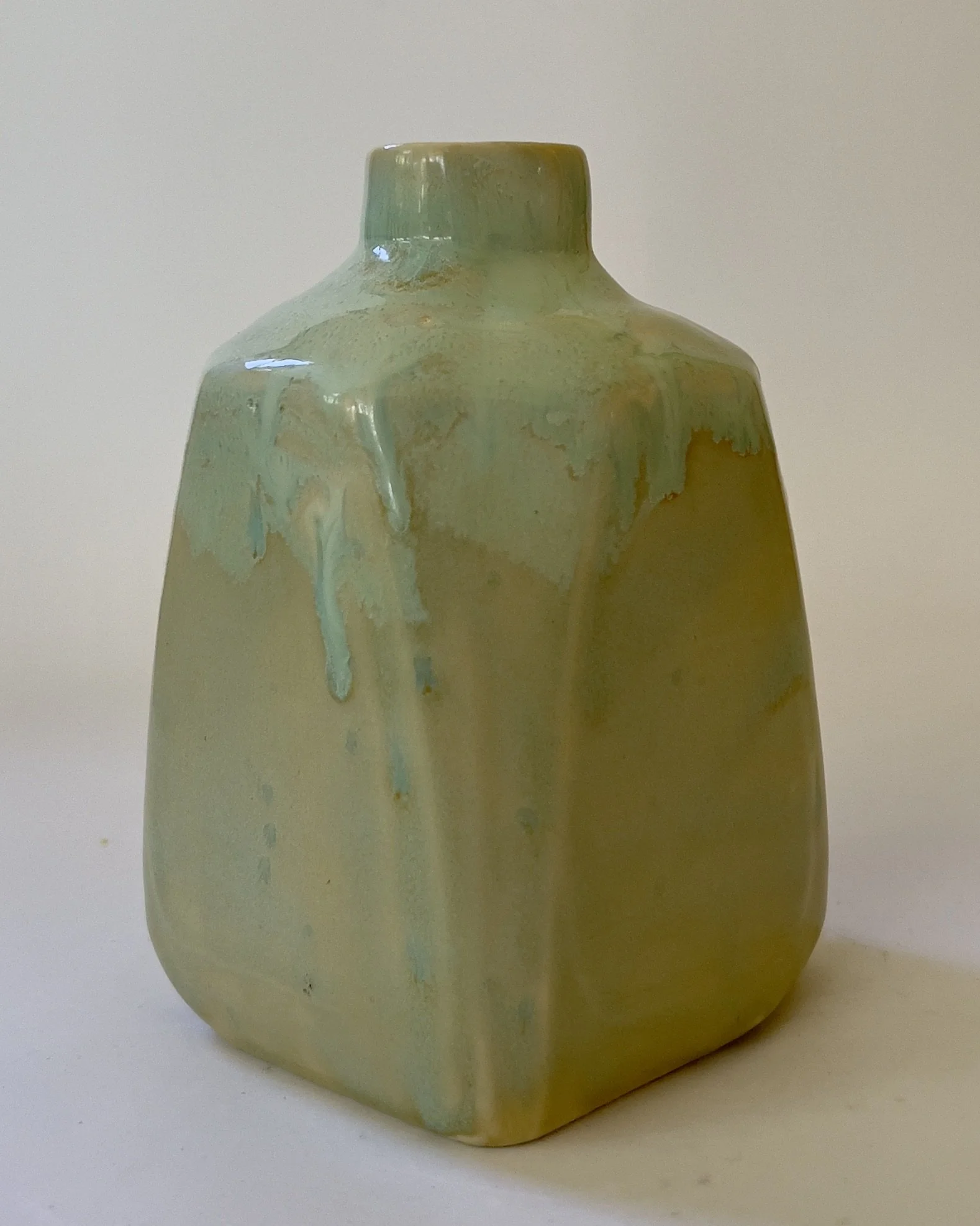Back view of sculptural ceramic milk jug with flowing celadon glaze