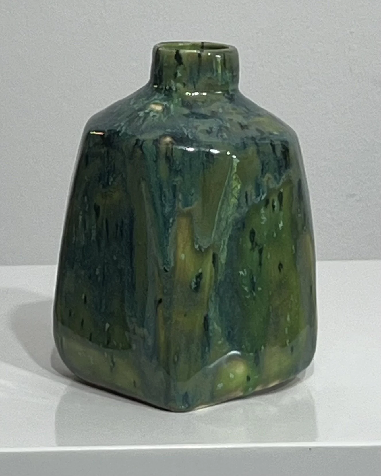 Left-side view of porcelain milk jug with glossy green and blue ceramic glazes.