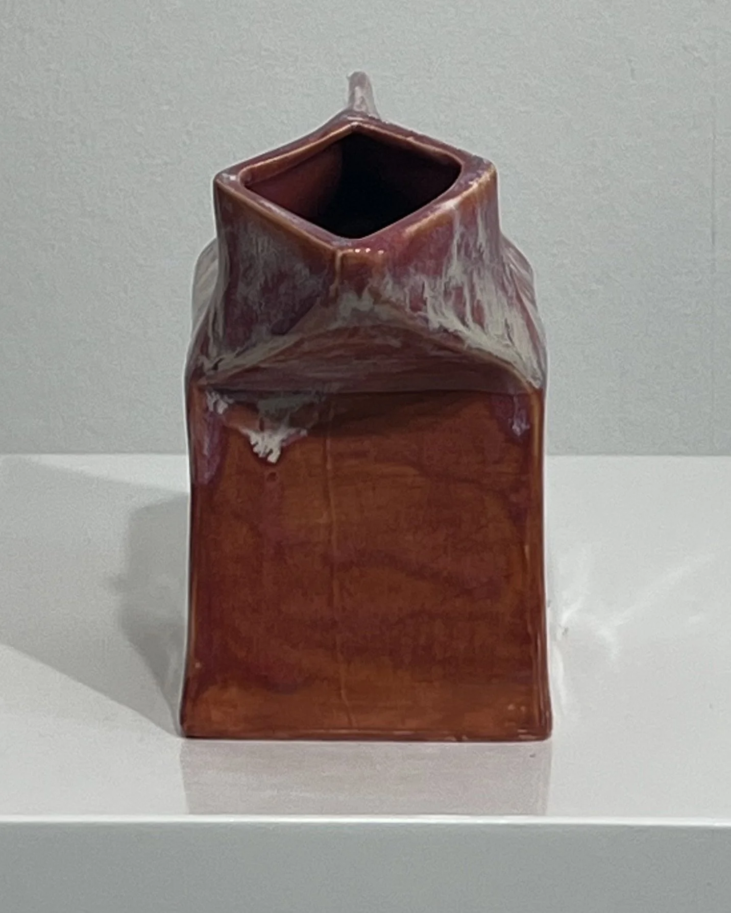 Back view of the handbuilt ceramic milk carton with rich rust red Chun Plum glaze and sculptural folded top.