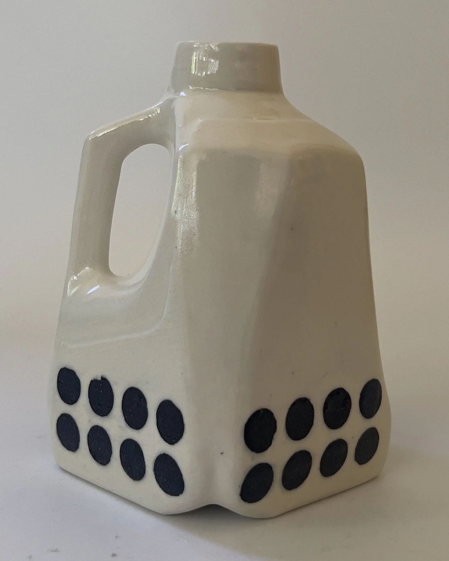 Contemporary ceramic vessel with black dot pattern and glossy white glaze