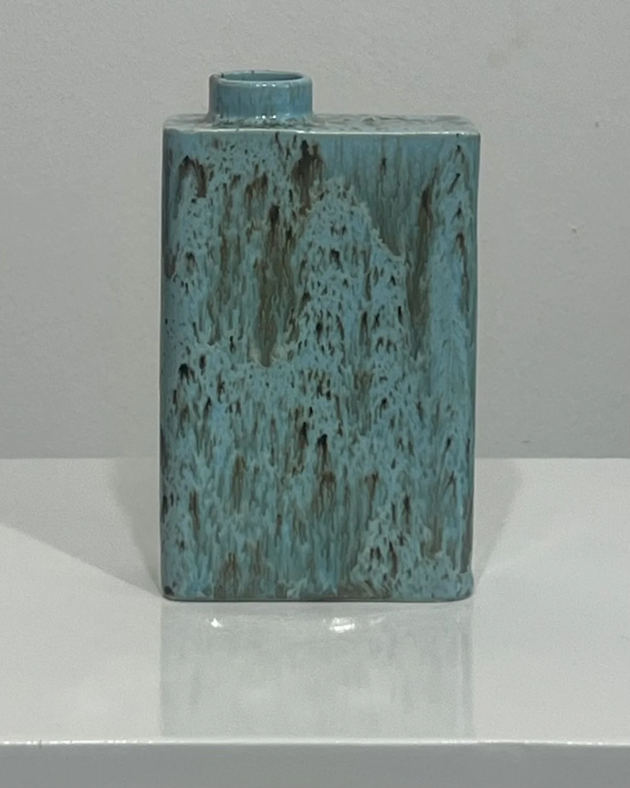 Front view of porcelain carton vase C26.7 finished in Cenote glaze with cascading turquoise and brown patterning.