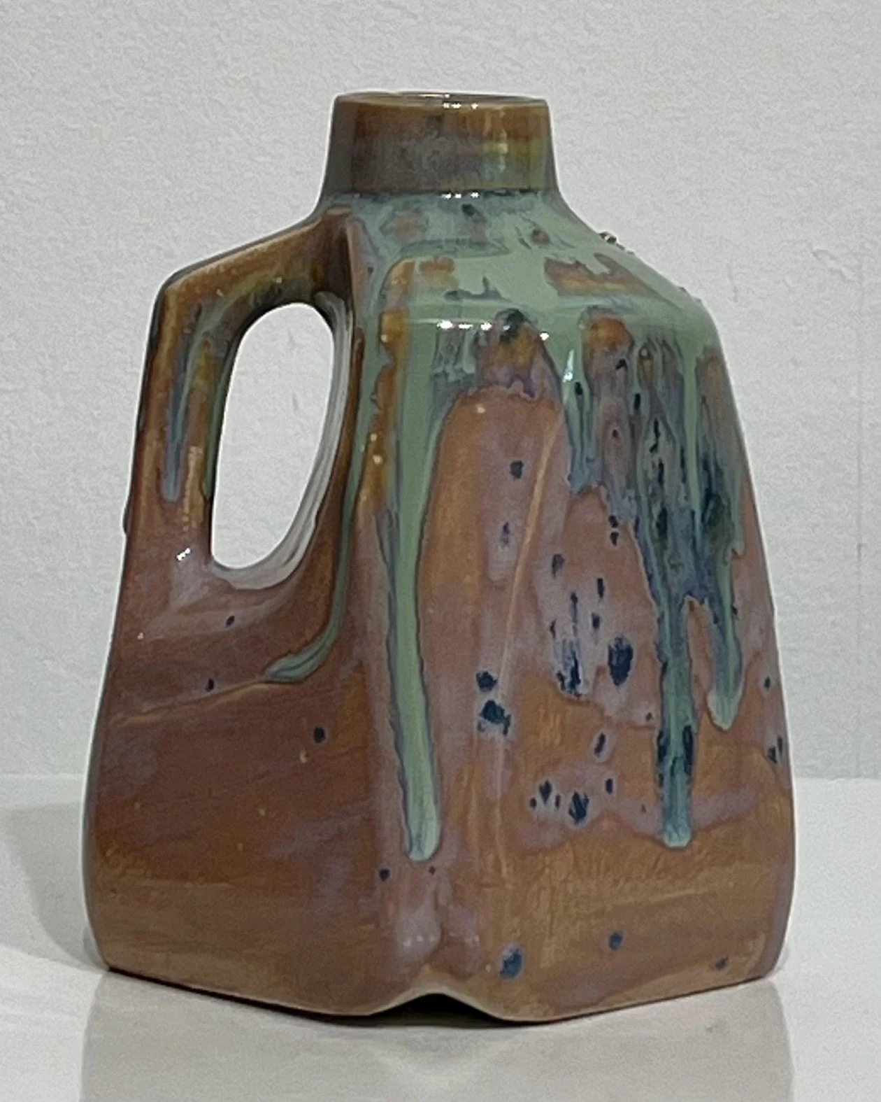 Back view of one-of-a-kind porcelain milk jug with earthy rose and turquoise glaze