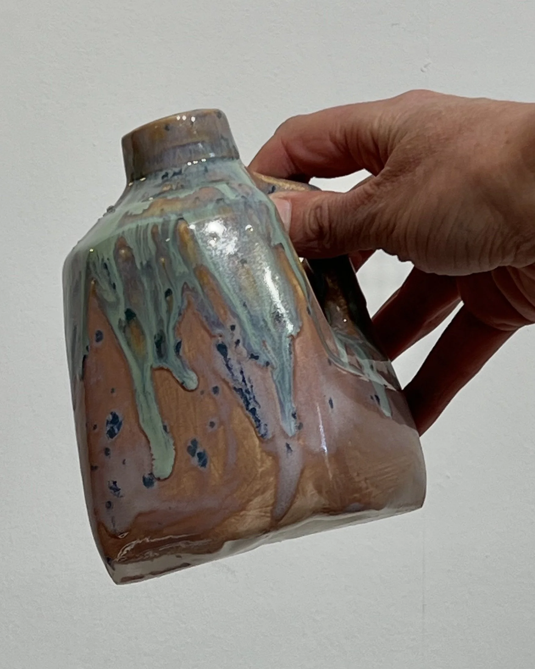 Handmade porcelain milk jug held in hand to demonstrate its compact size