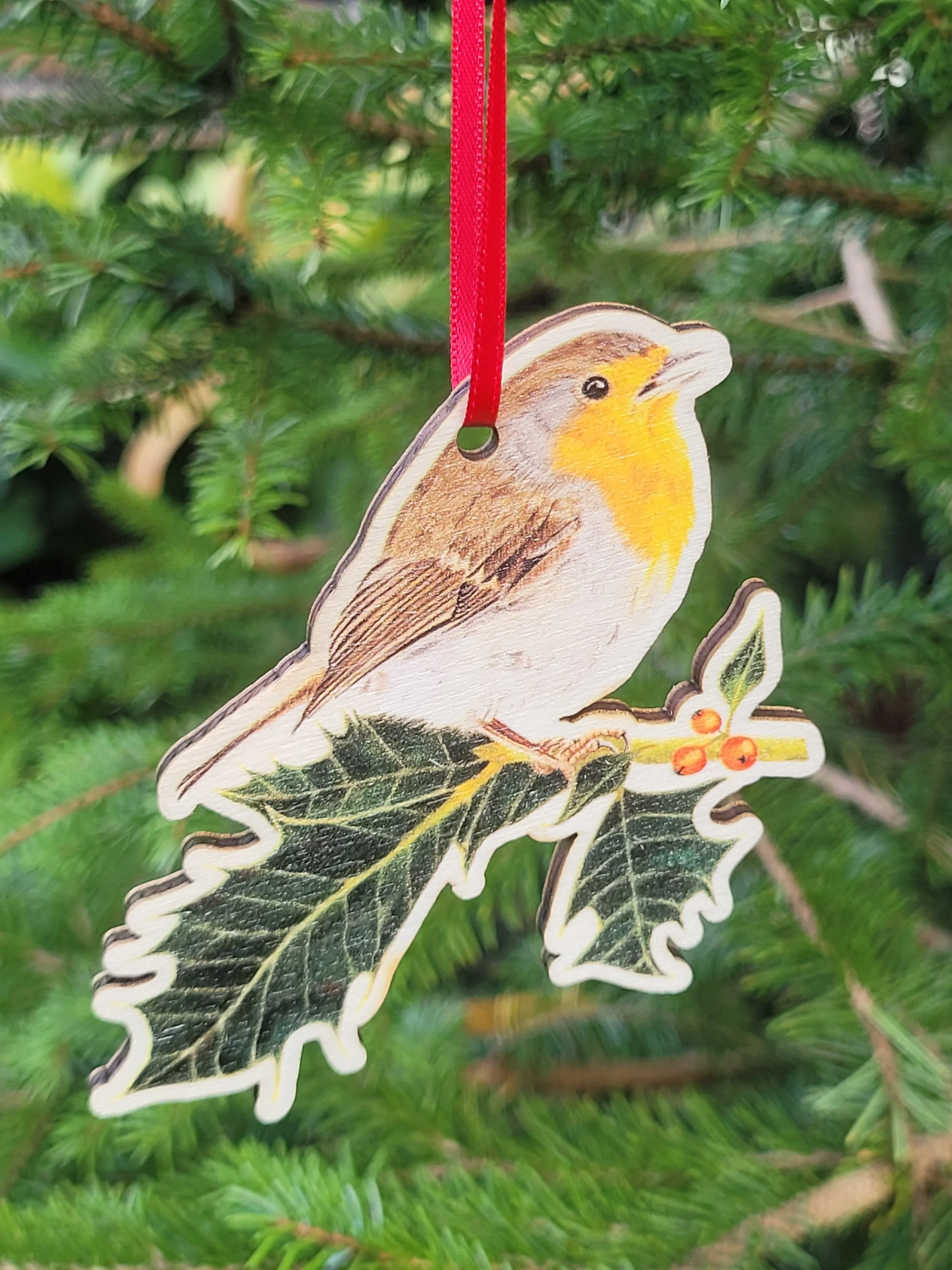 A robin on holly wooden Christmas decoration with a red ribbon.