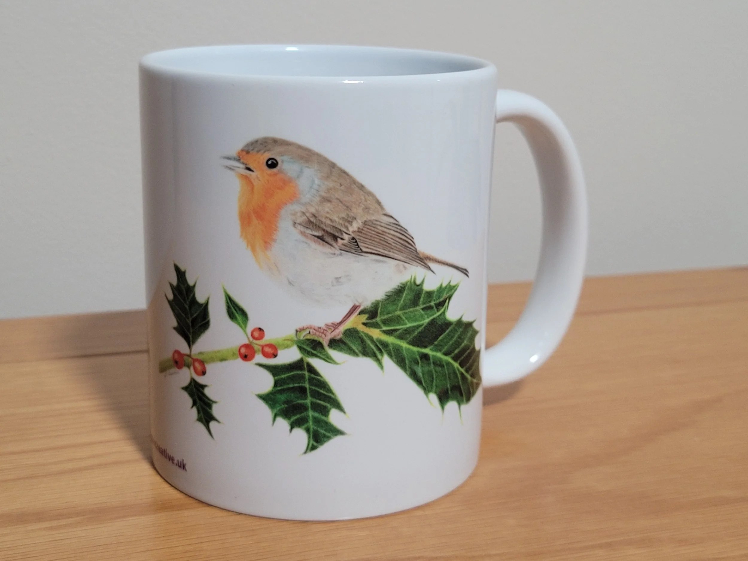 Robin sitting on holly mug.