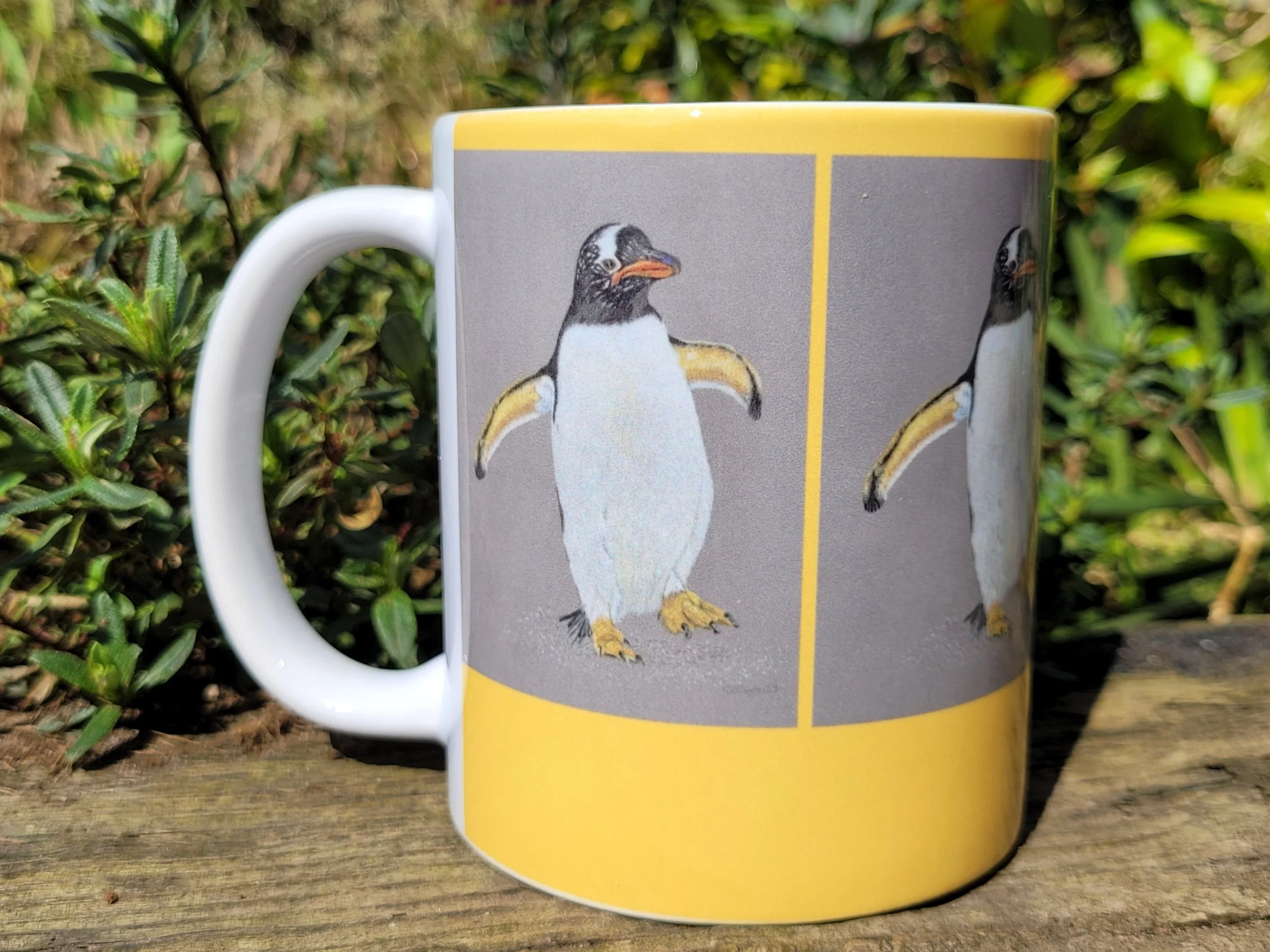 A Gentoo penguin ceramic mug with a yellow background.