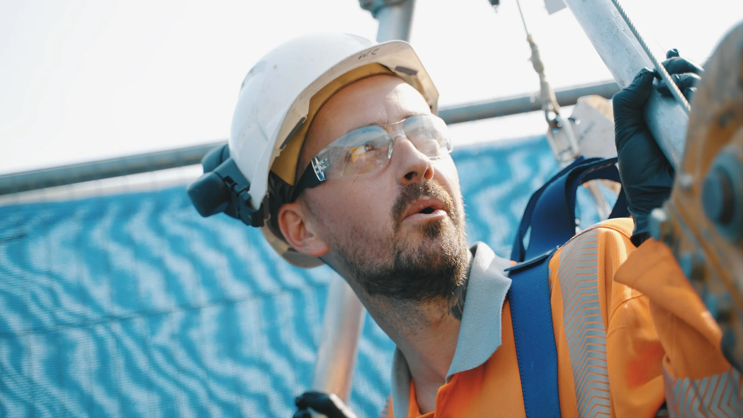 Construction worker wearing safety gear inspecting equipment at a construction site.