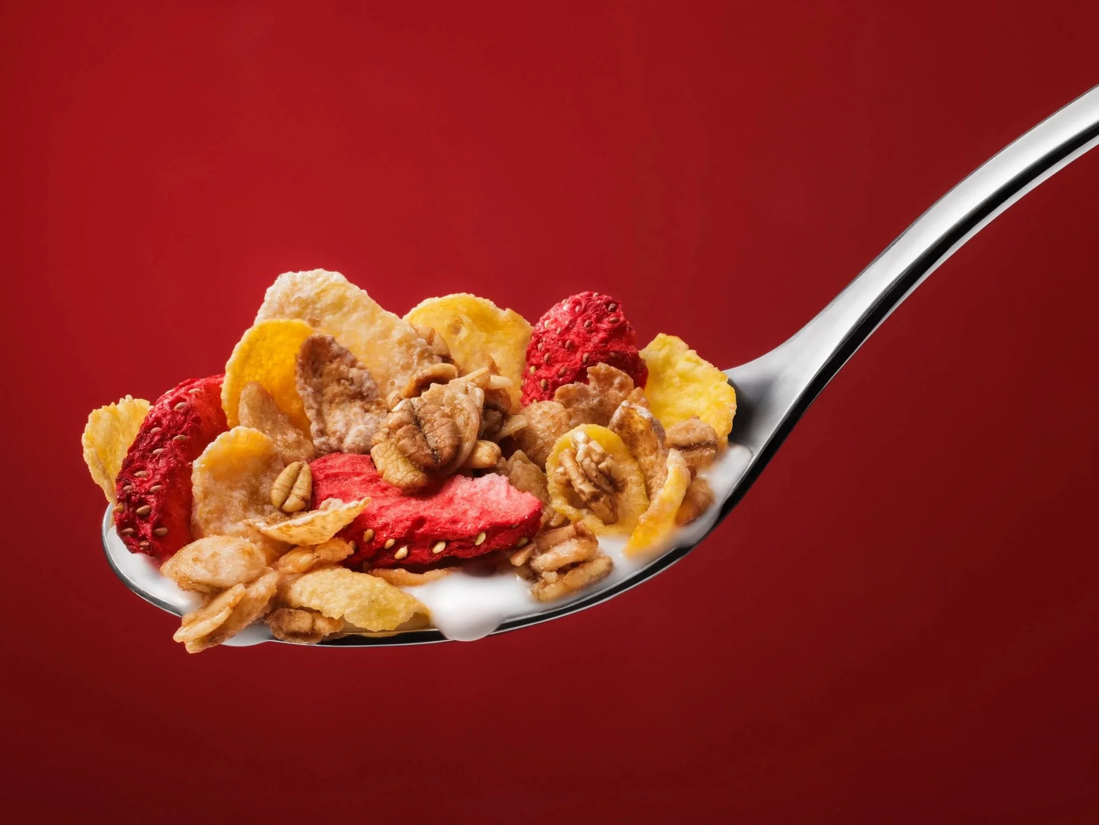 NYC commercial food product photography featuring cereal, granola, freeze-dried fruit, and milk on a spoon for packaged food brand advertising.