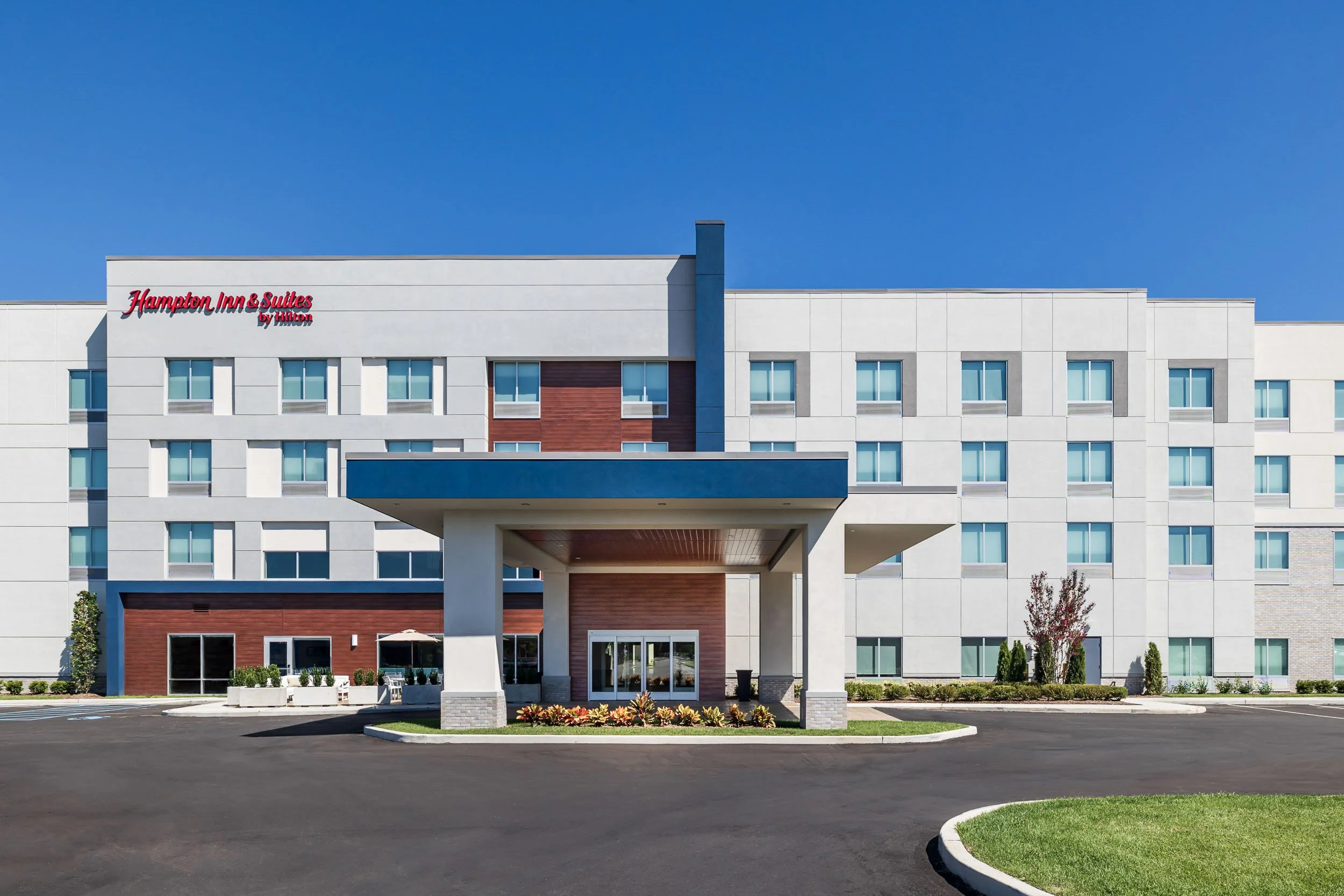 Hampton Inn and Suites by Hilton exterior architecture, professional hospitality building photography, commercial hotel facade with modern entrance canopy, upscale corporate lodging photography, architectural branding for hospitality developers.