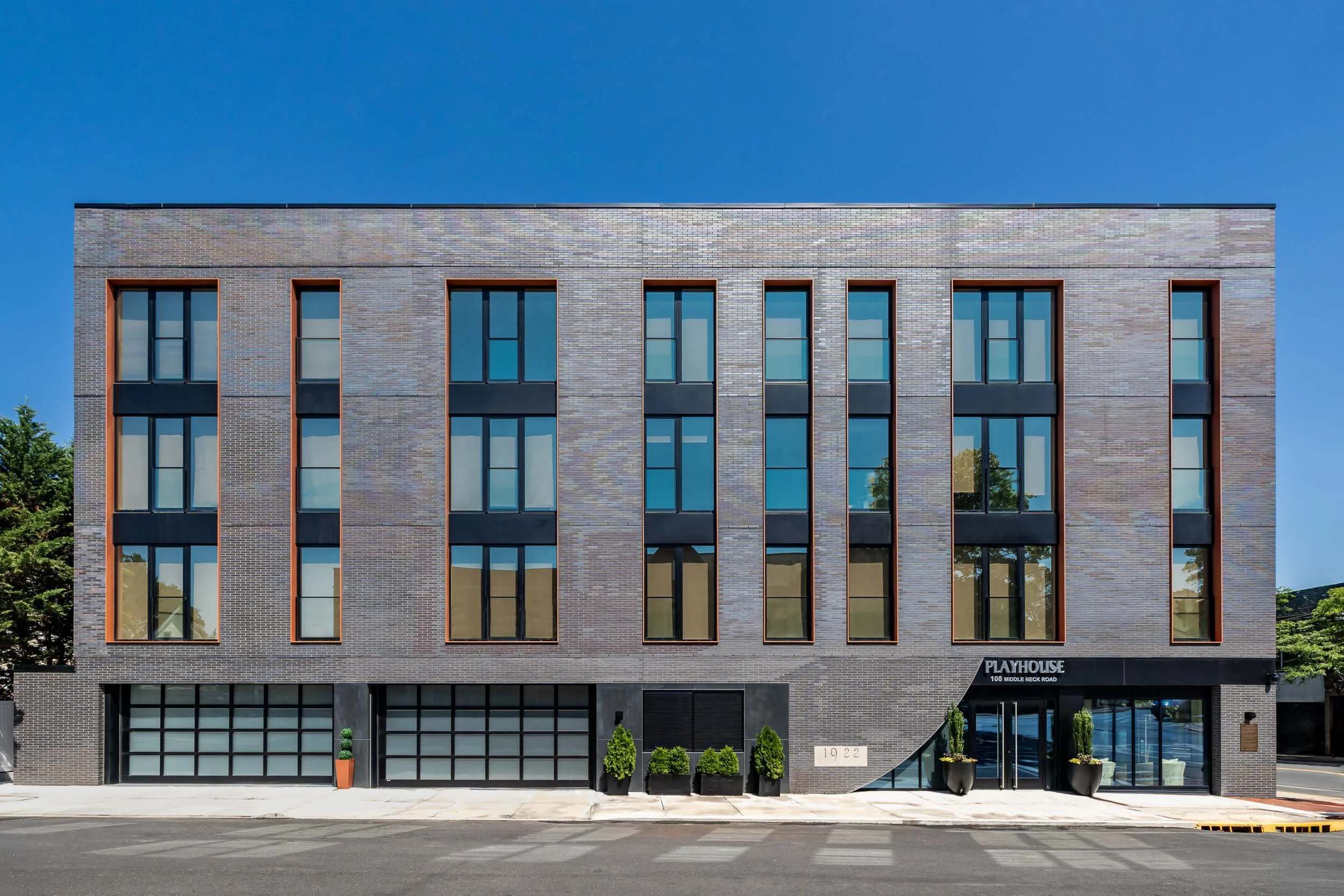 Modern grey brick architectural elevation photography, professional exterior shot of mixed-use commercial building, contemporary facade with dark metal window frames and geometric glass doors, architectural material detail and rhythm, urban commercia