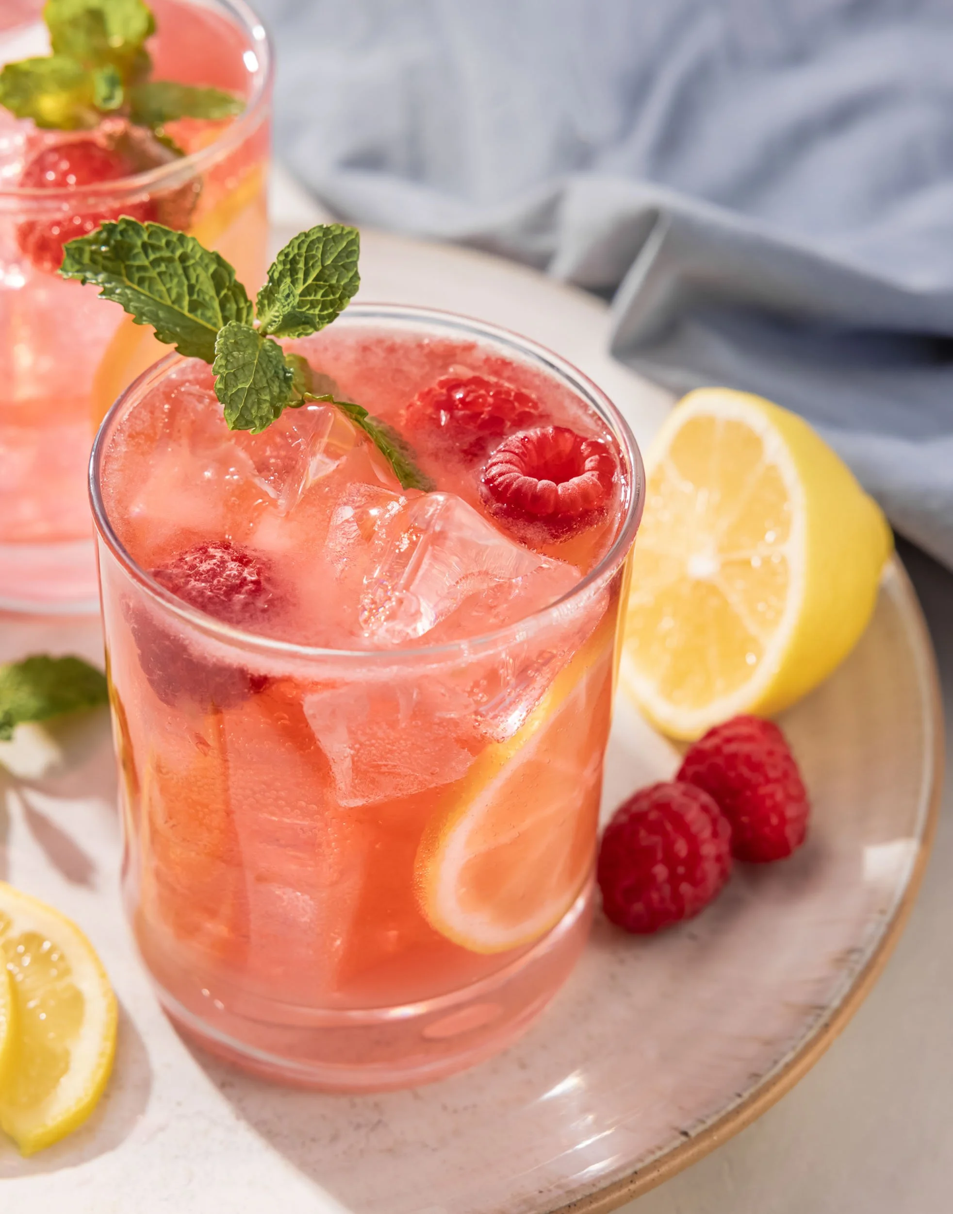Refreshing raspberry lemonade cocktail photography, summer beverage branding, professional drink styling with ice and mint garnish, seasonal hospitality advertising imagery, vibrant fruit-forward cocktail photography for social media.