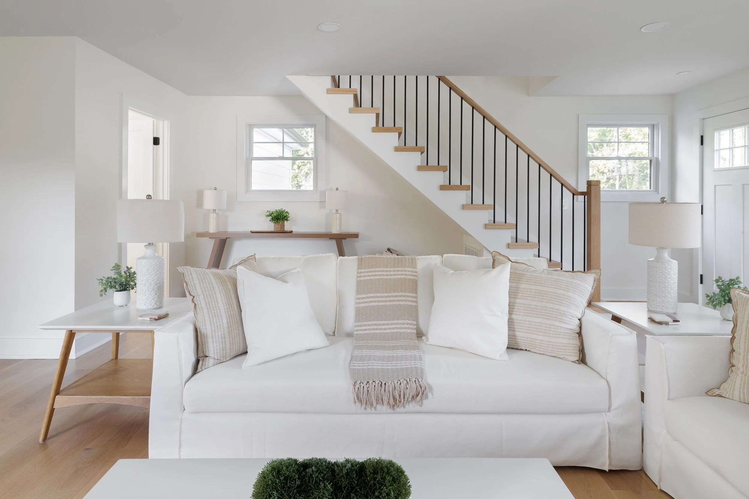 Bright open-concept living room architectural photography, high-end residential interior design with white neutral palette, professional photography of modern staircase and lounge area, airy interior architecture with natural lighting, minimalist lux