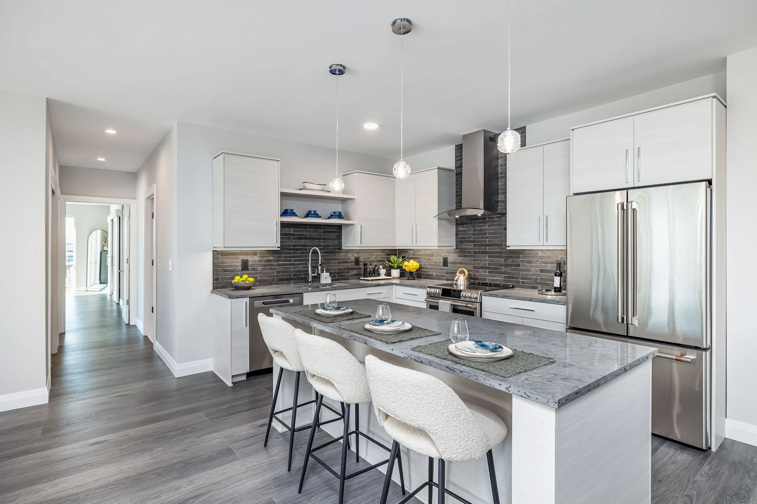Modern kitchen interior photography, high-end residential kitchen with granite island and pendant lighting, professional architectural photography of white cabinetry and stainless steel appliances, open concept kitchen design with dark wood flooring,