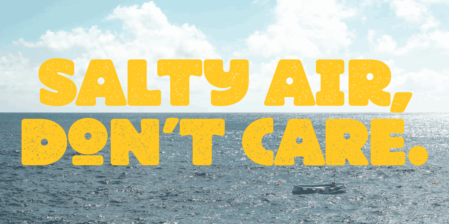 A sign in the ocean with the text 'Salty Air, Don't Care' written in large yellow letters over the water and sky background.