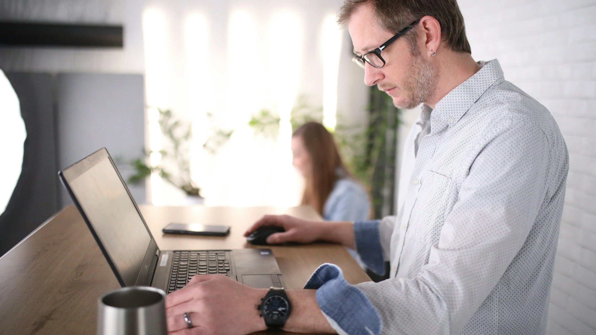 A man sat at a desk looking at his laptop.