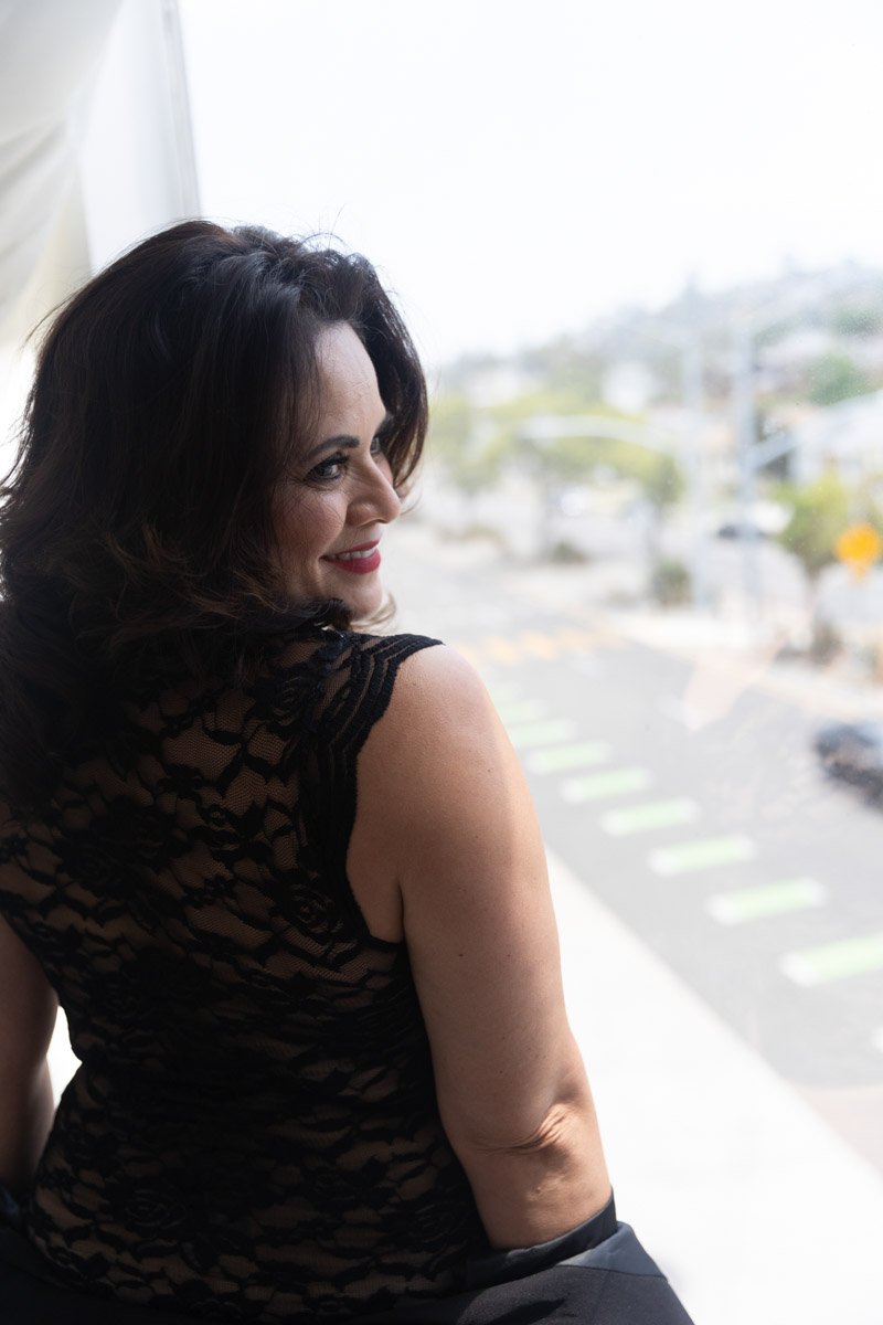  Boudoir portrait of older Latina woman looking out from a balcony 