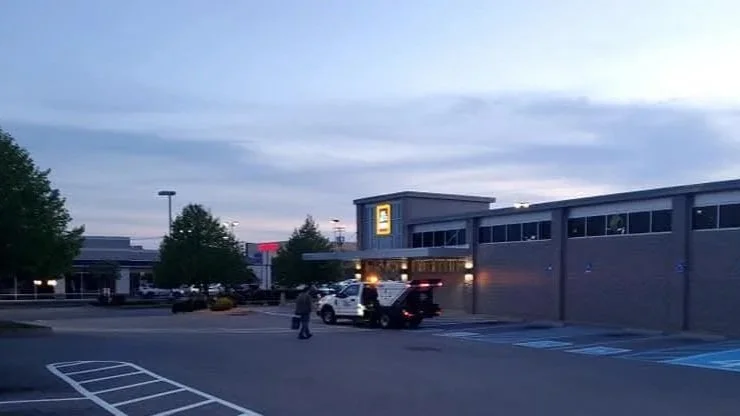 A parking lot outside a Lowe's store during early evening with a few cars parked and one person walking in front of the store.