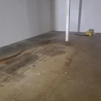 Empty room with a concrete floor and a wall with pipes or conduits attached.