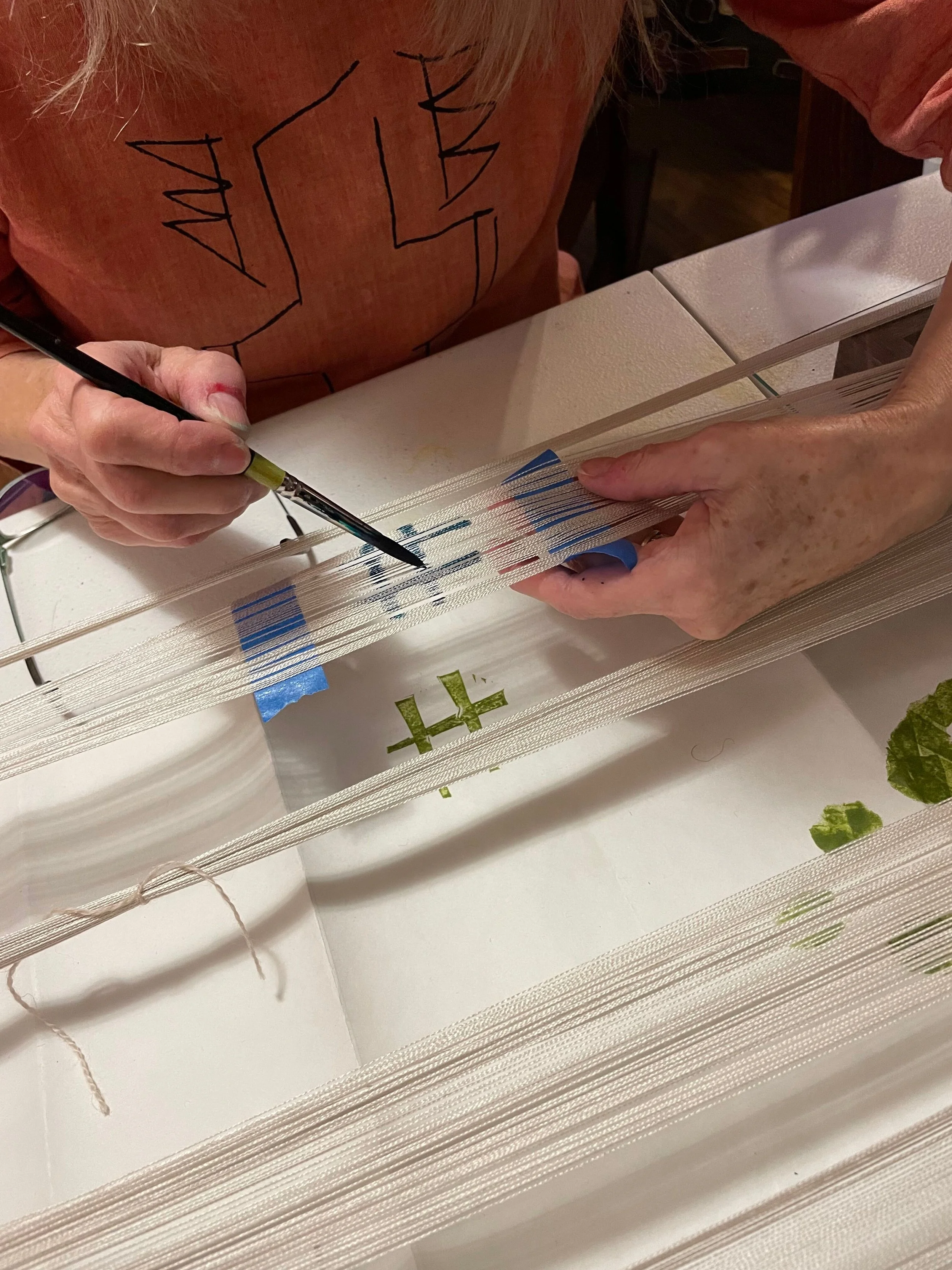 hands painting on warp threads