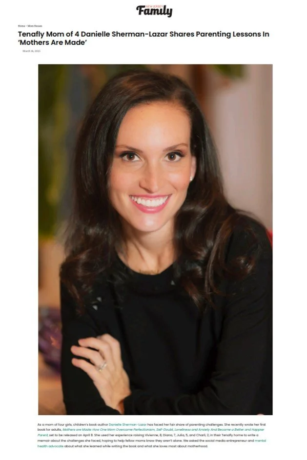 A woman with long brown hair, smiling and wearing a black top, is sitting with her arms crossed.