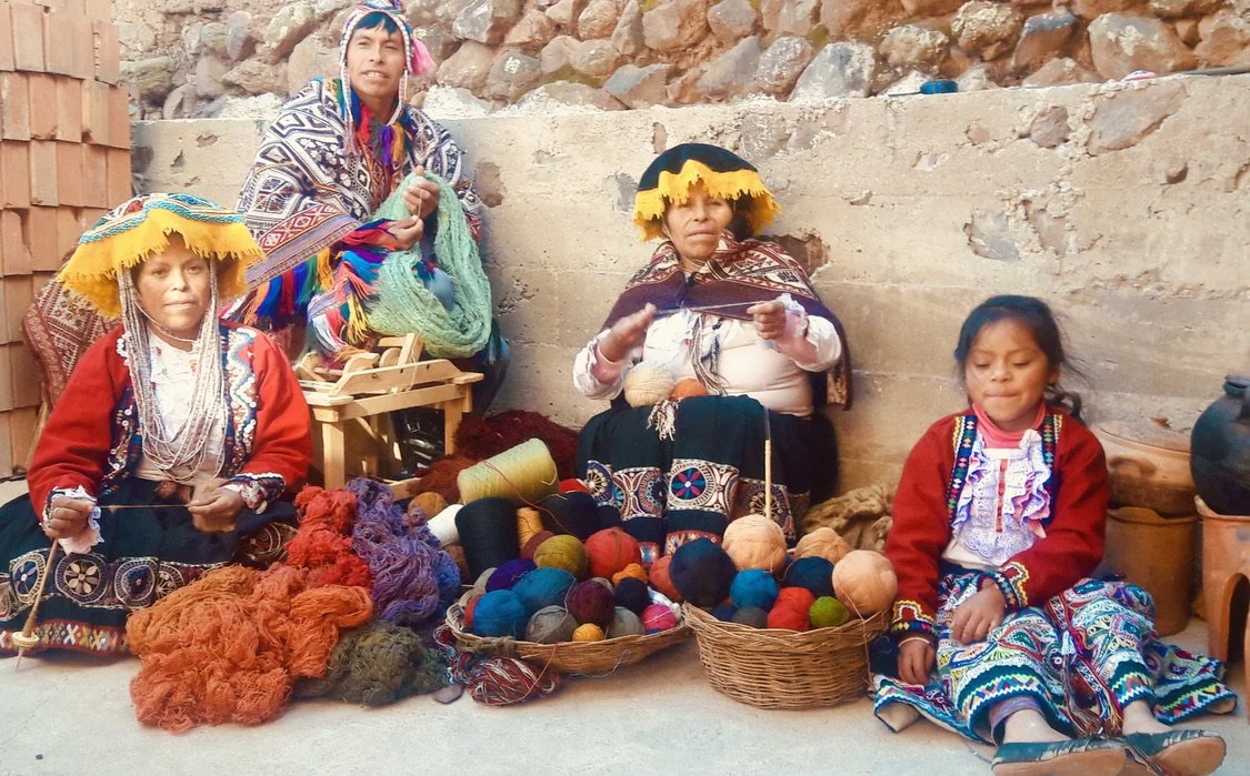 artists in traditional clothing with skeens of yarn