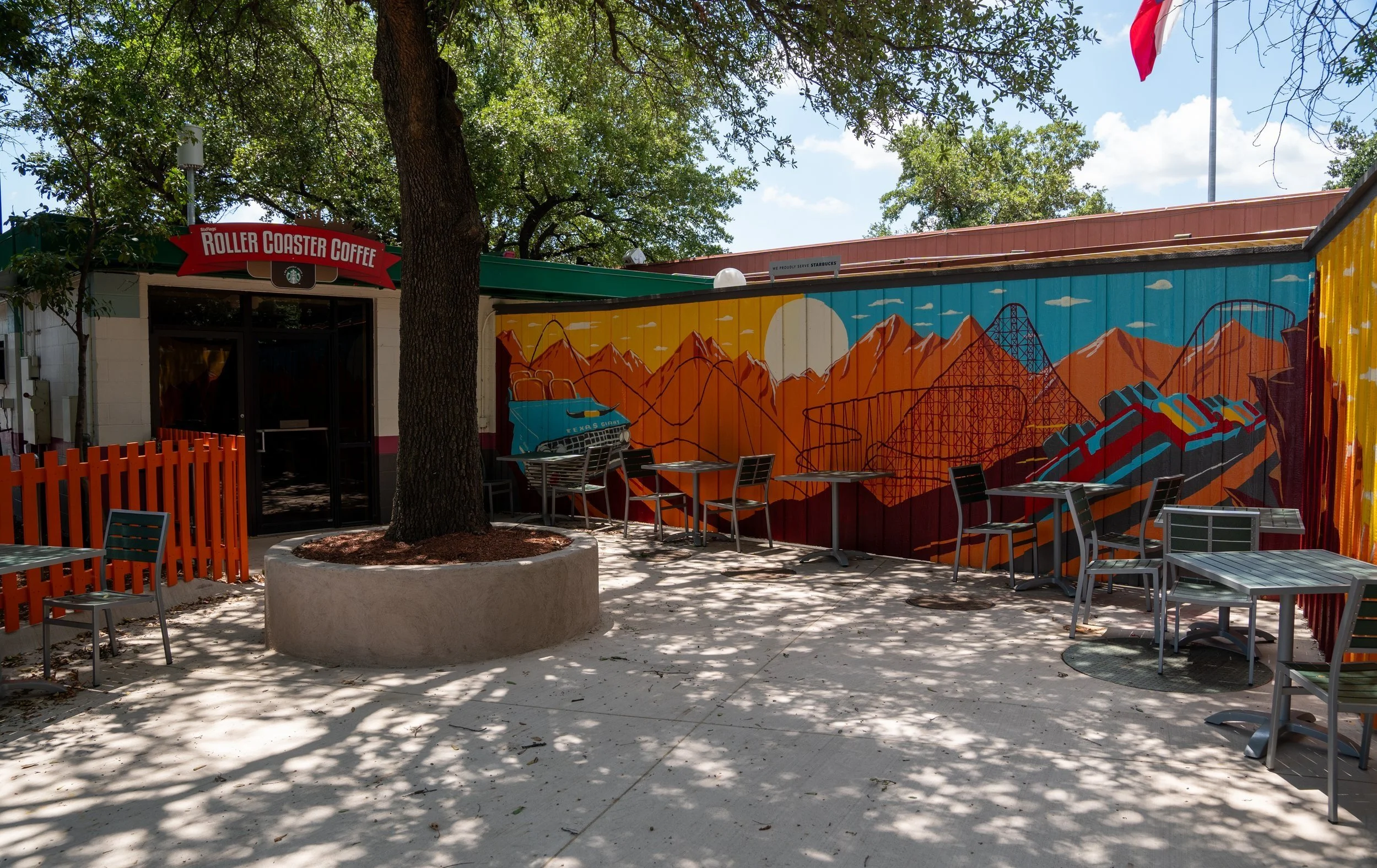 Outdoor seating area of Roller Coaster Coffee with colorful mural and tables.