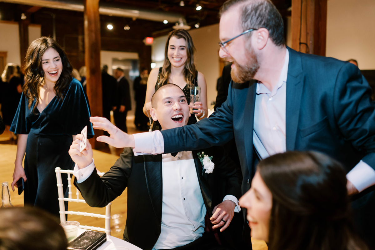 A groom reacting to a card trick at his wedding reception